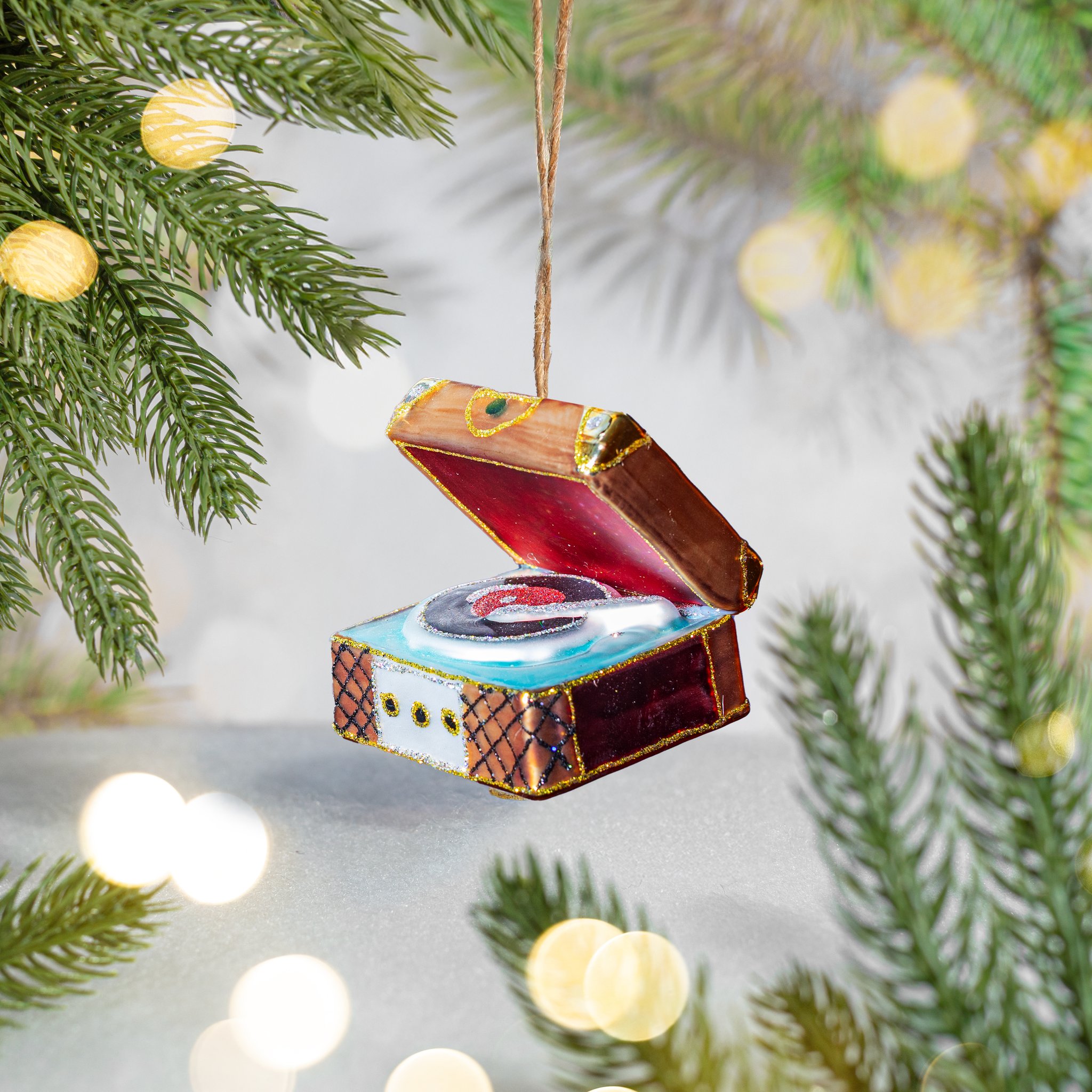 Glass record player ornament hanging from a fir branch