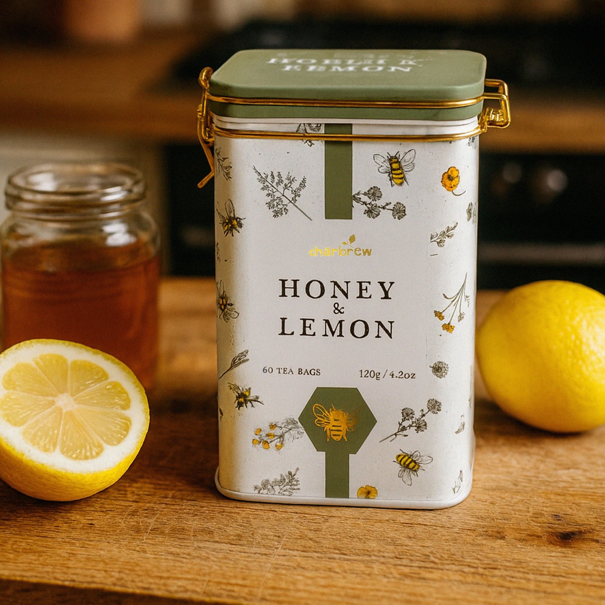 Latta di tè Honey & Lemon su un tagliere di legno accanto a limoni e un vasetto di miele