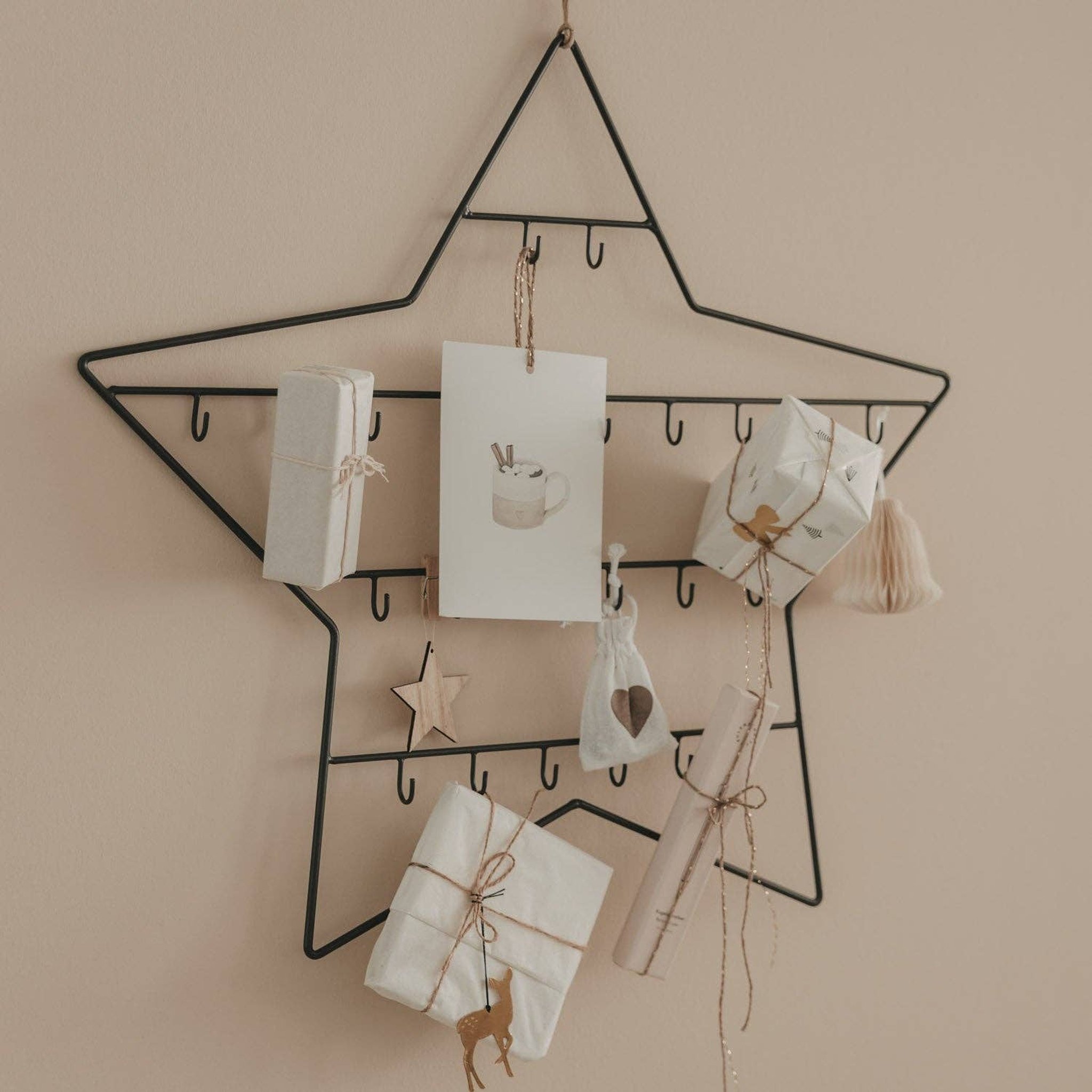 Calendario dell'Avvento stella in metallo nero con pacchetti bianchi, biglietti e sacchettini