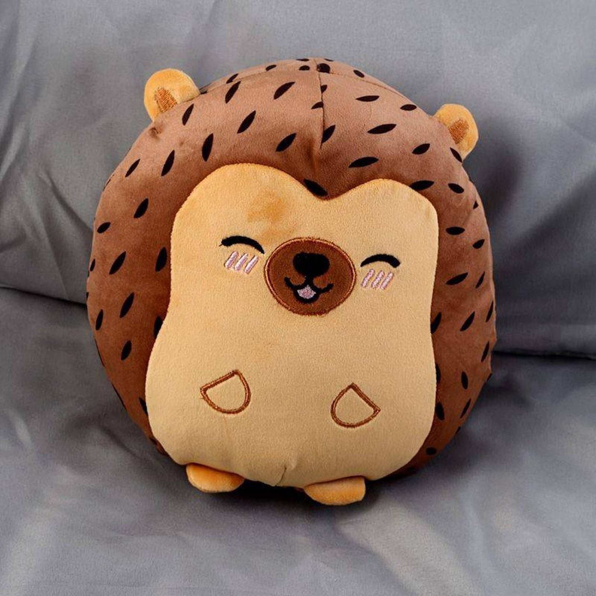 Hedgehog plush cushion on a grey blanket
