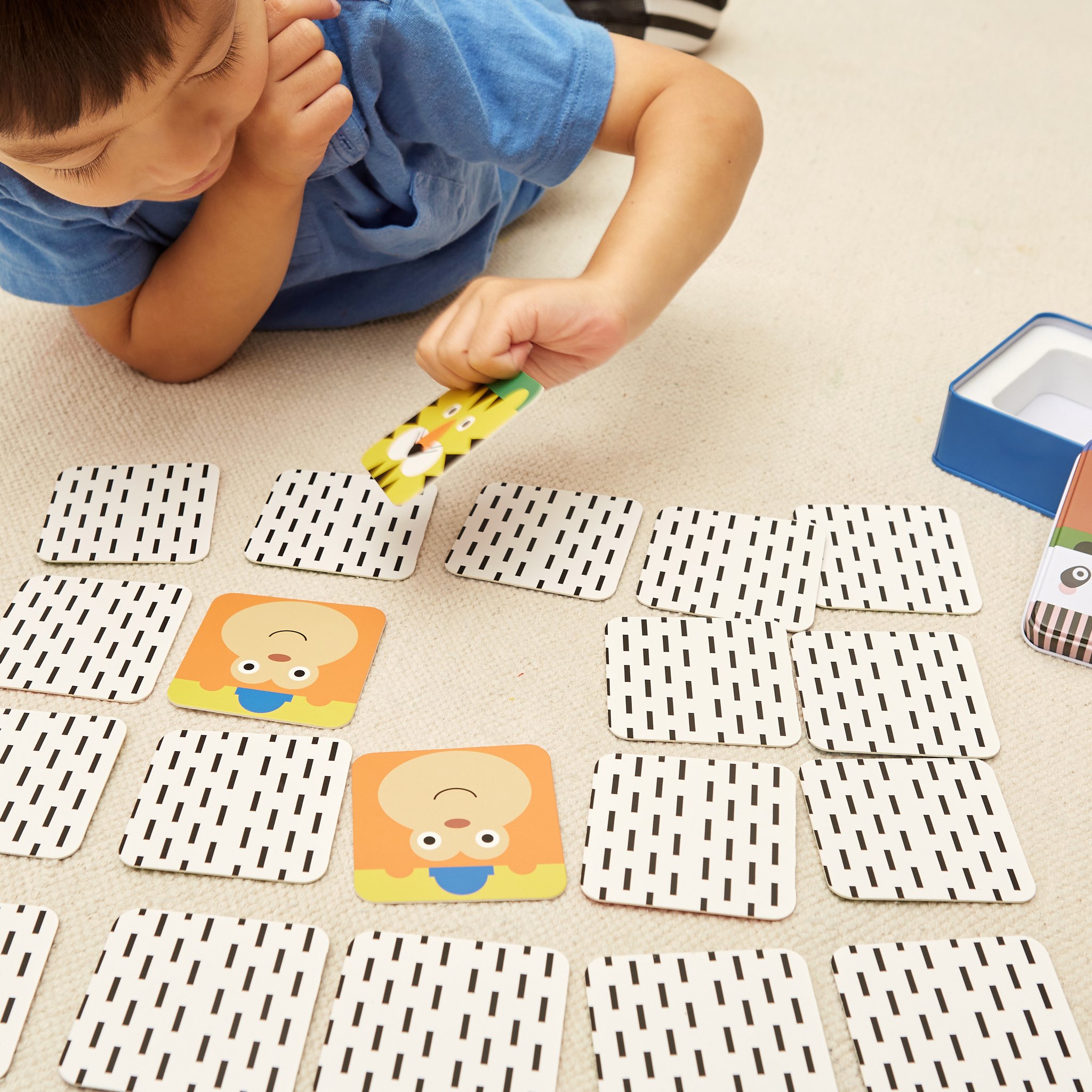 Boy playing the travel memory game with animal cards on the floor