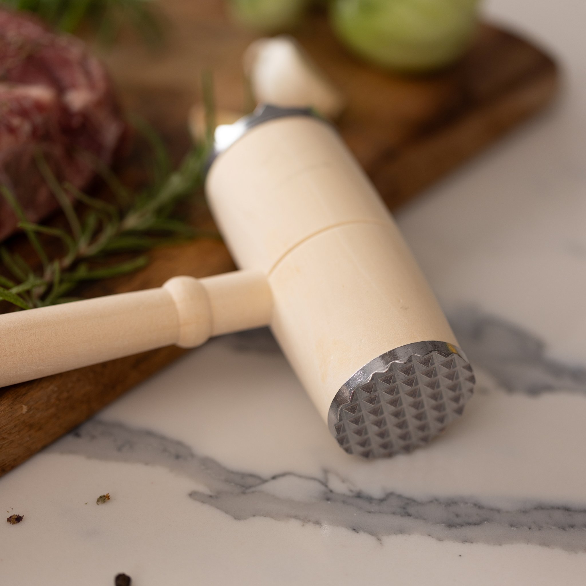 Detail of the BBQ Lovers Kit tenderizer: the studded metal face of the head resting on white marble