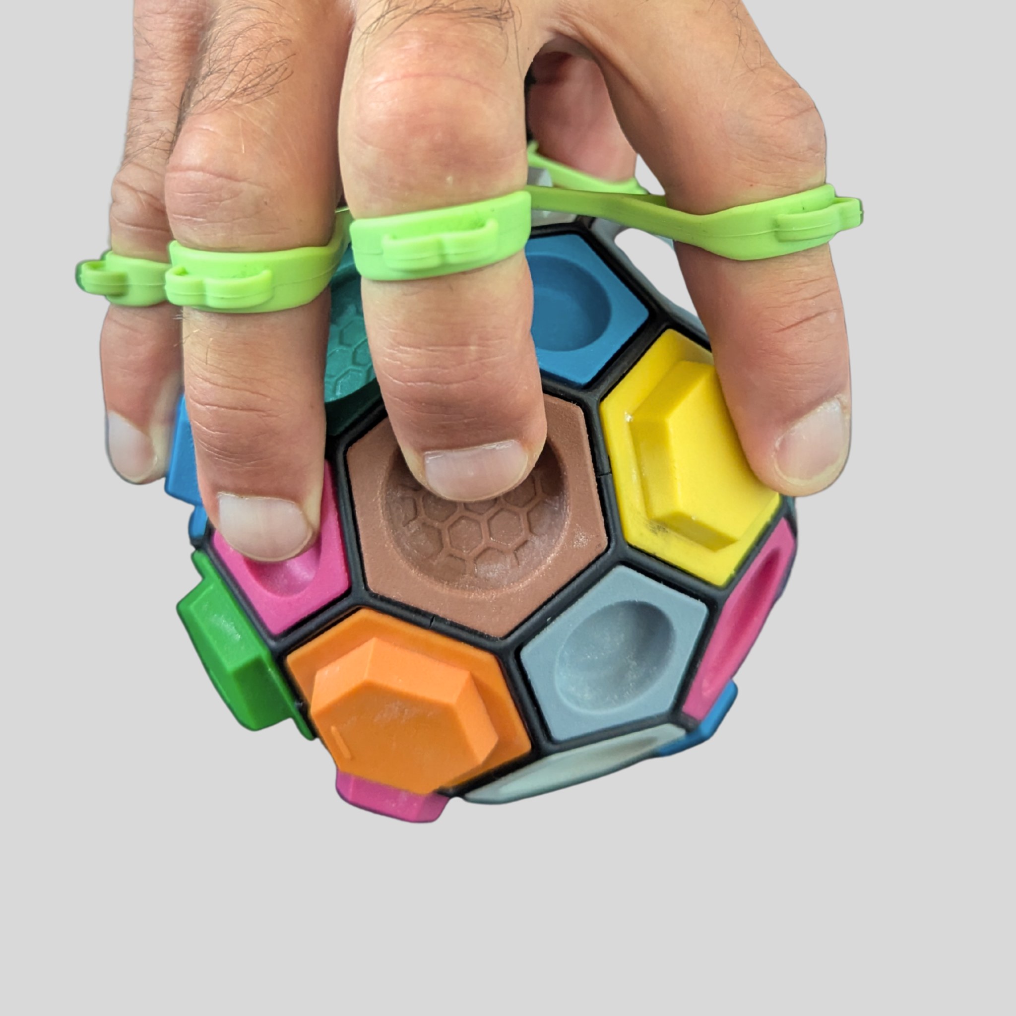 Mano che tiene il Boulderball con le dita nell'elastico verde del set POWER