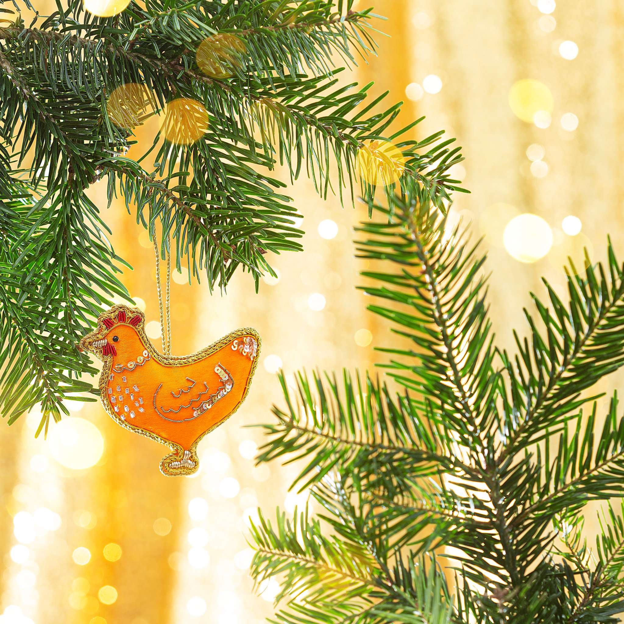 Décoration de Noël poule zari Sass & Belle, poule brodée orange et or sur une branche de sapin