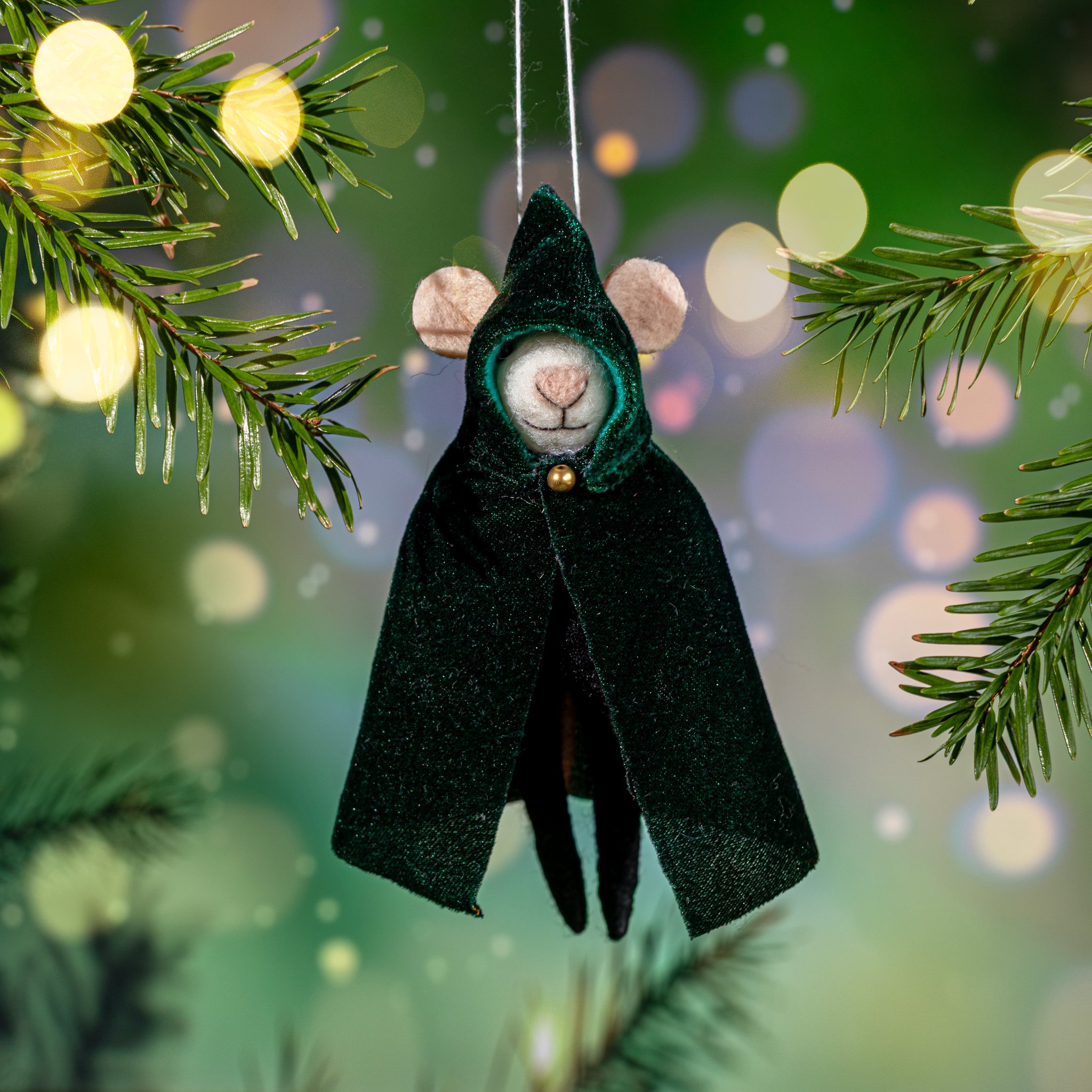 Felt mouse with green cape hanging from a fir branch
