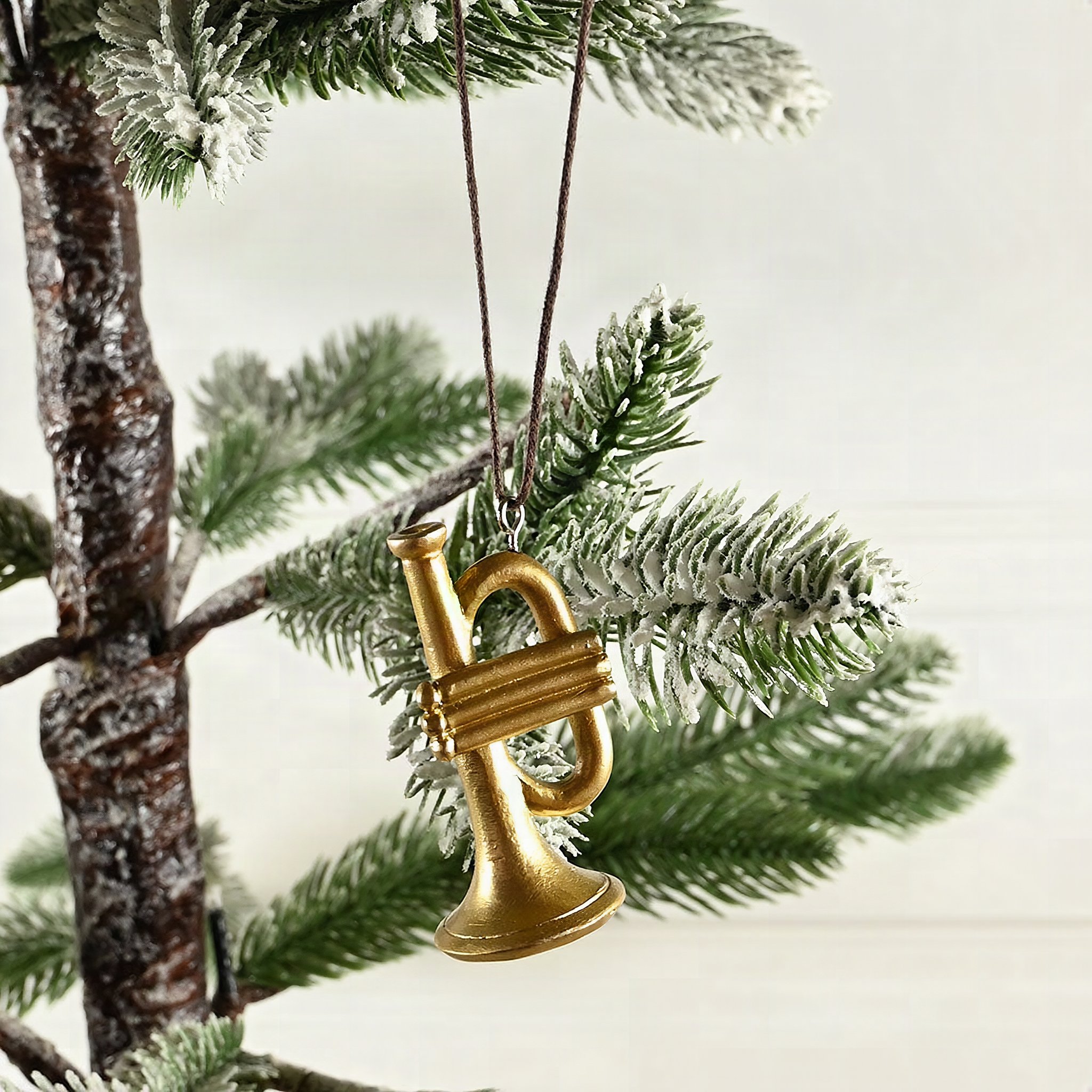 Goldene Trompete zum Aufhängen an einem beschneiten Tannenzweig