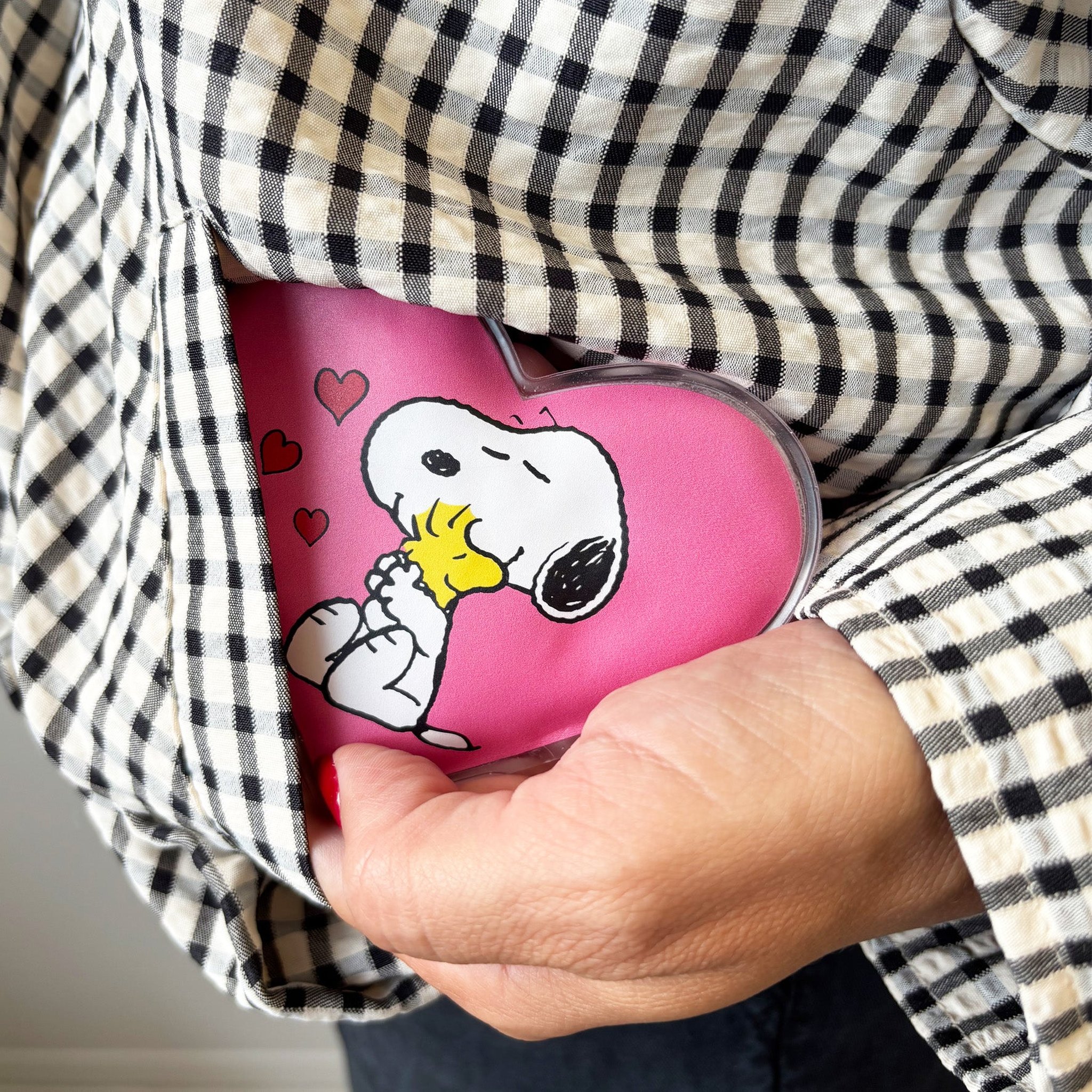 Snoopy Handwärmer wird in die Tasche eines karierten Hemds gesteckt