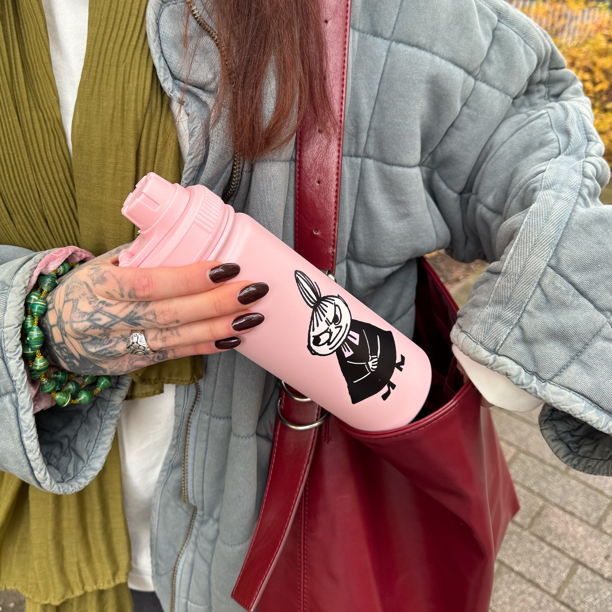 Woman putting the pink Little My thermal bottle into her shoulder bag