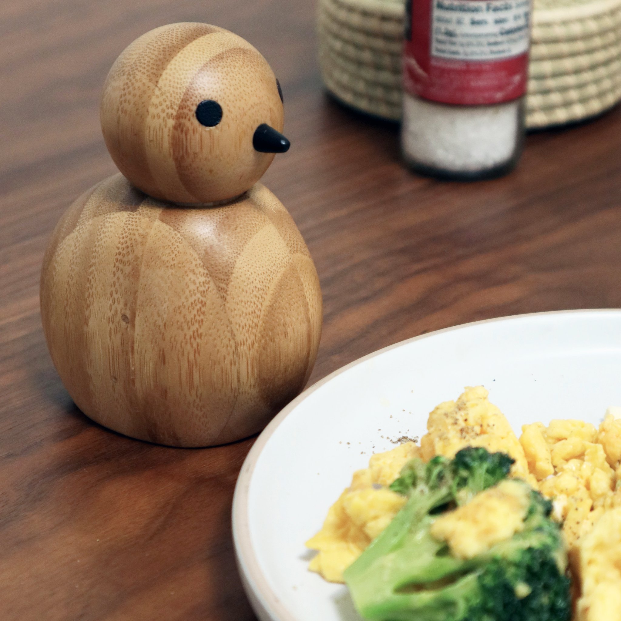 Moulin à sel et poivre Birdy en bois à côté d'une assiette d'oeufs brouillés et brocoli