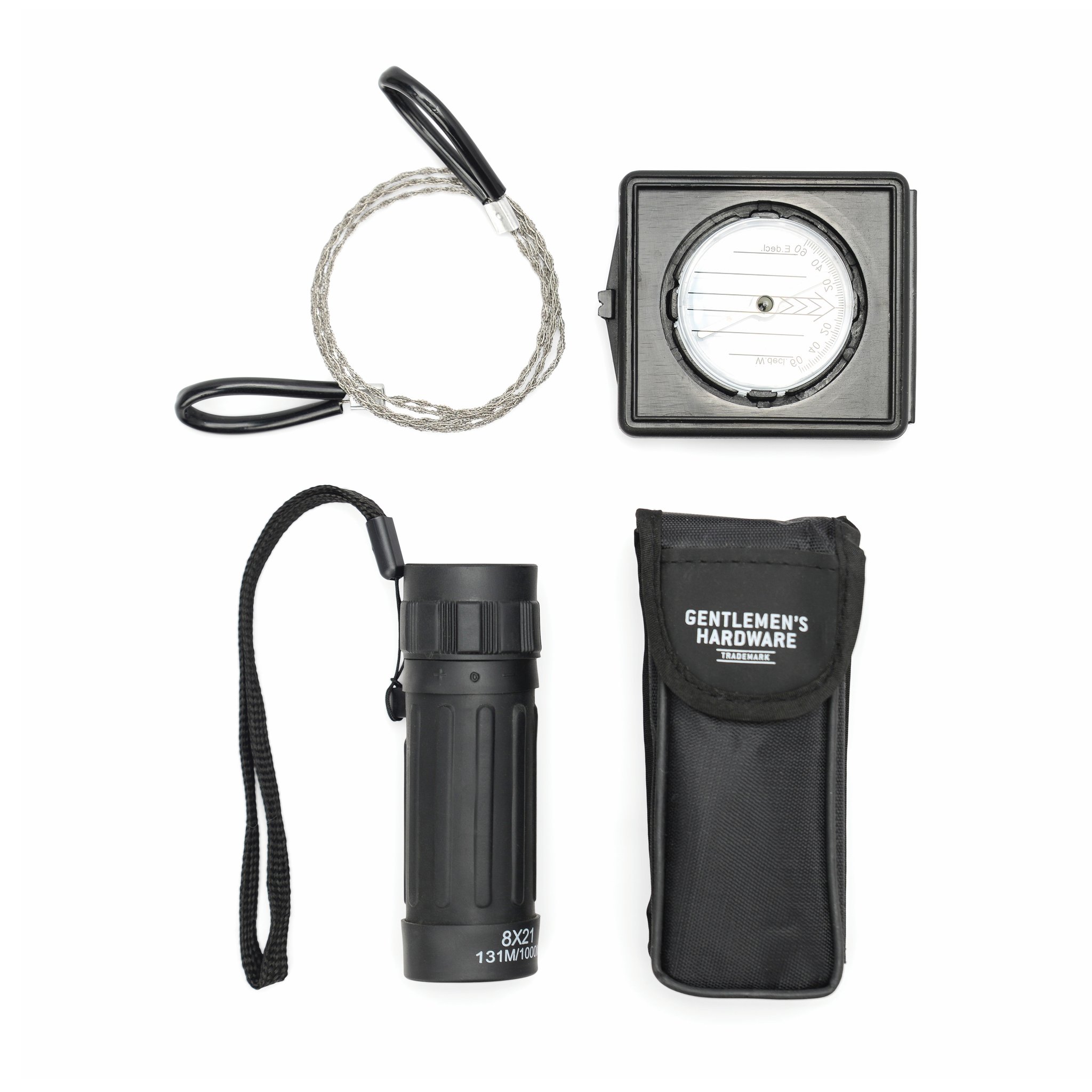 Kit d'exploration déballé sur fond blanc : scie à fil, boussole, monoculaire avec dragonne et étui noir