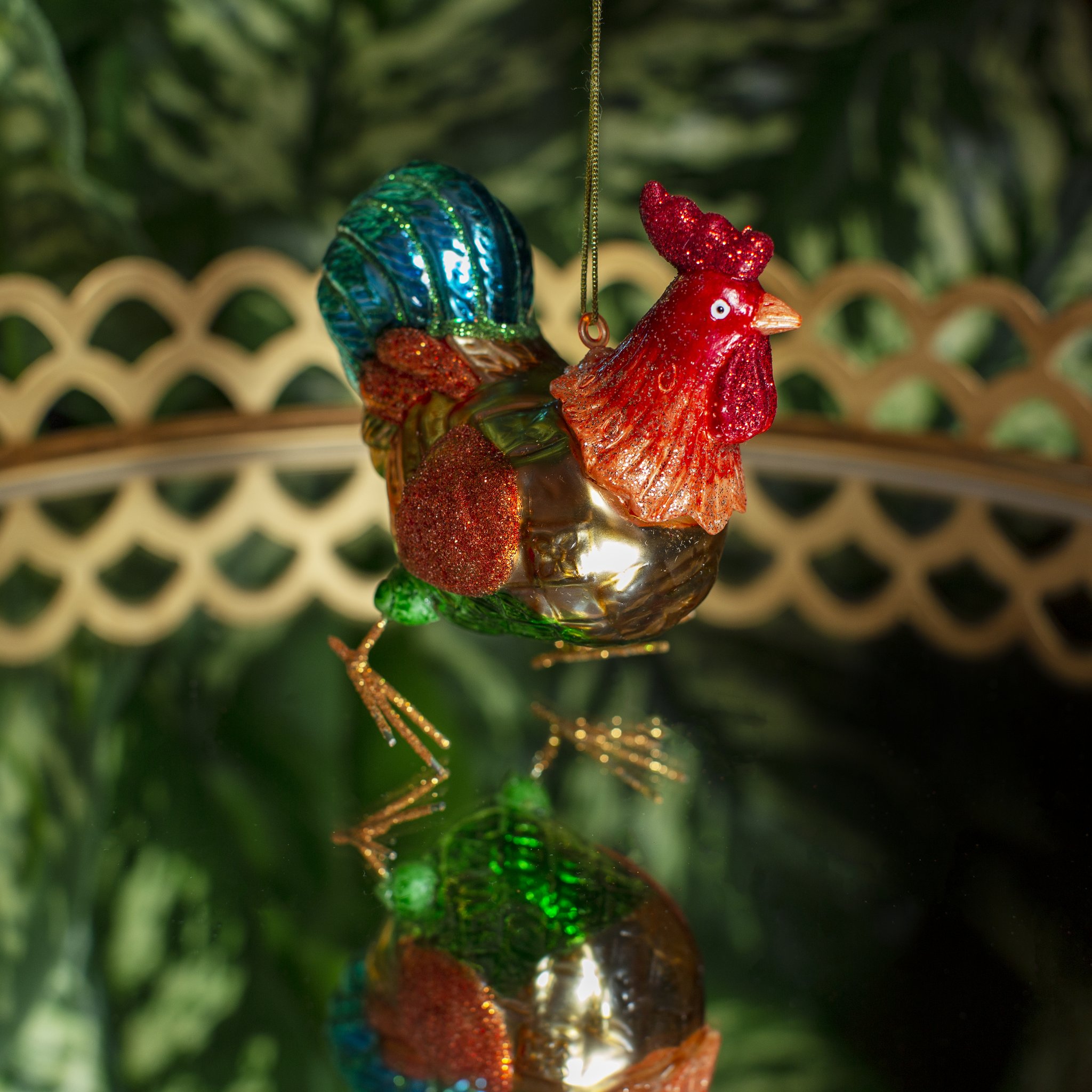 Décoration de Noël coq Sass & Belle, coq en verre rouge, or et bleu sur une branche de sapin