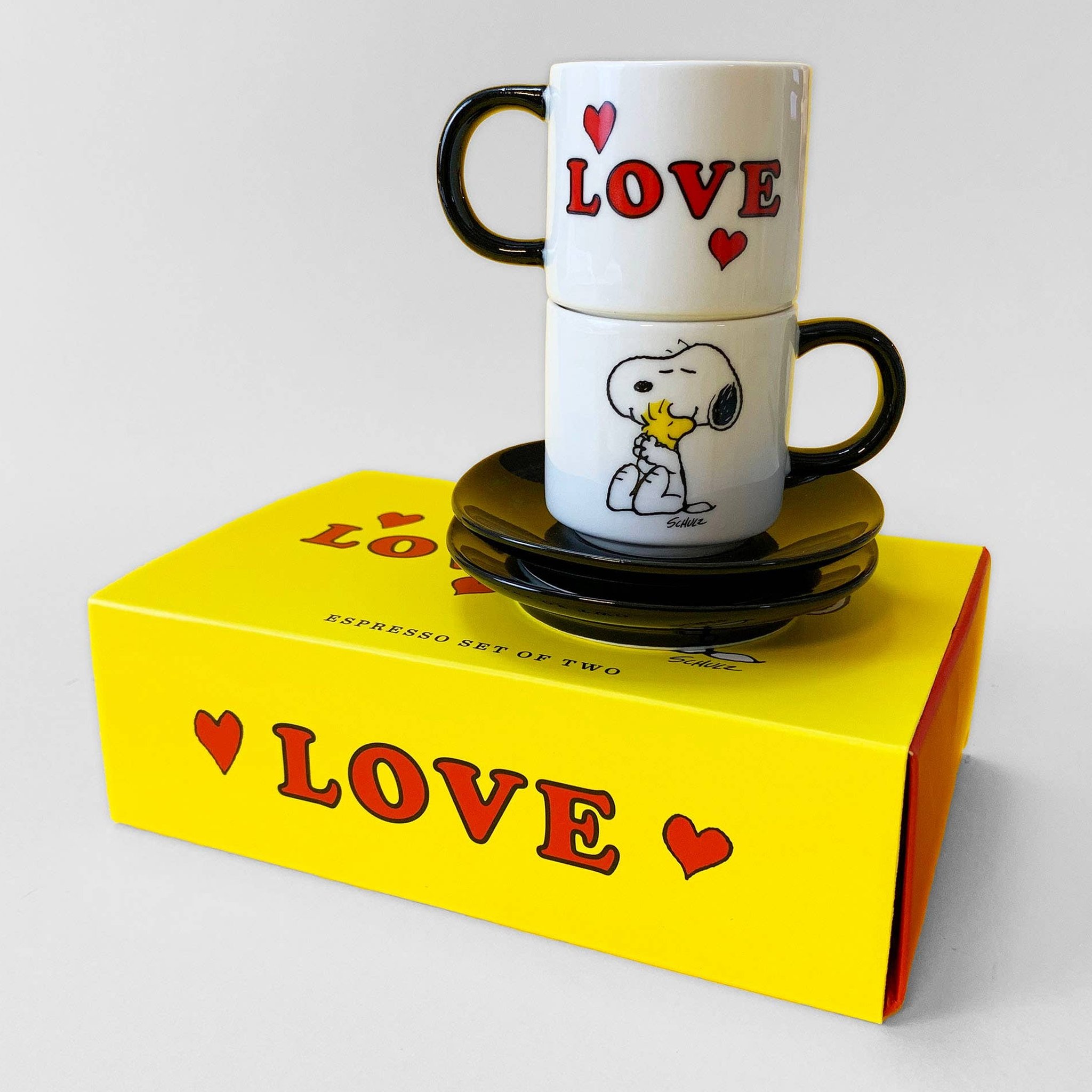 Snoopy Espressotassen-Set Love: zwei gestapelte Tassen mit Untertassen auf der gelben Geschenkbox