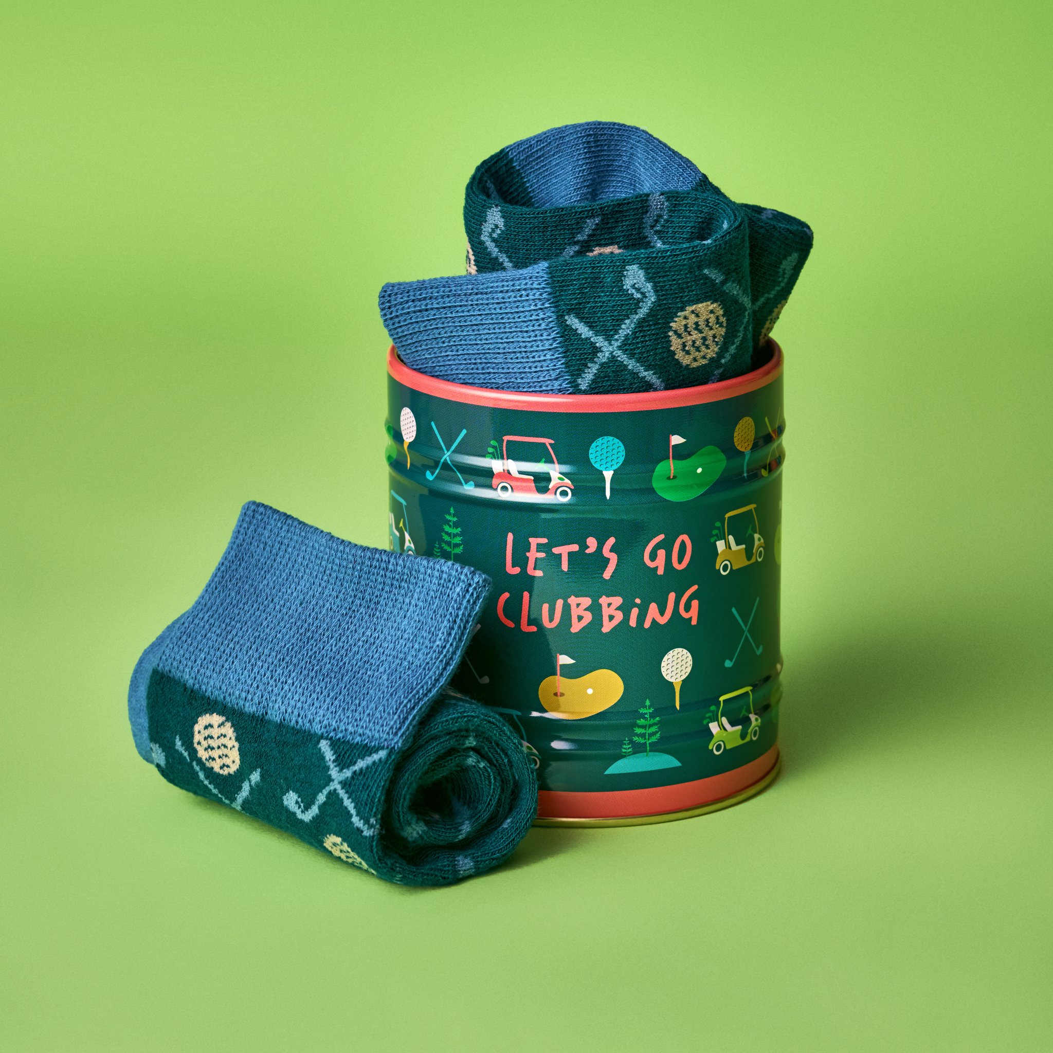 Golf-Sockenset auf grünem Hintergrund: Dose mit herausragender Socke, eine zweite Socke eingerollt davor
