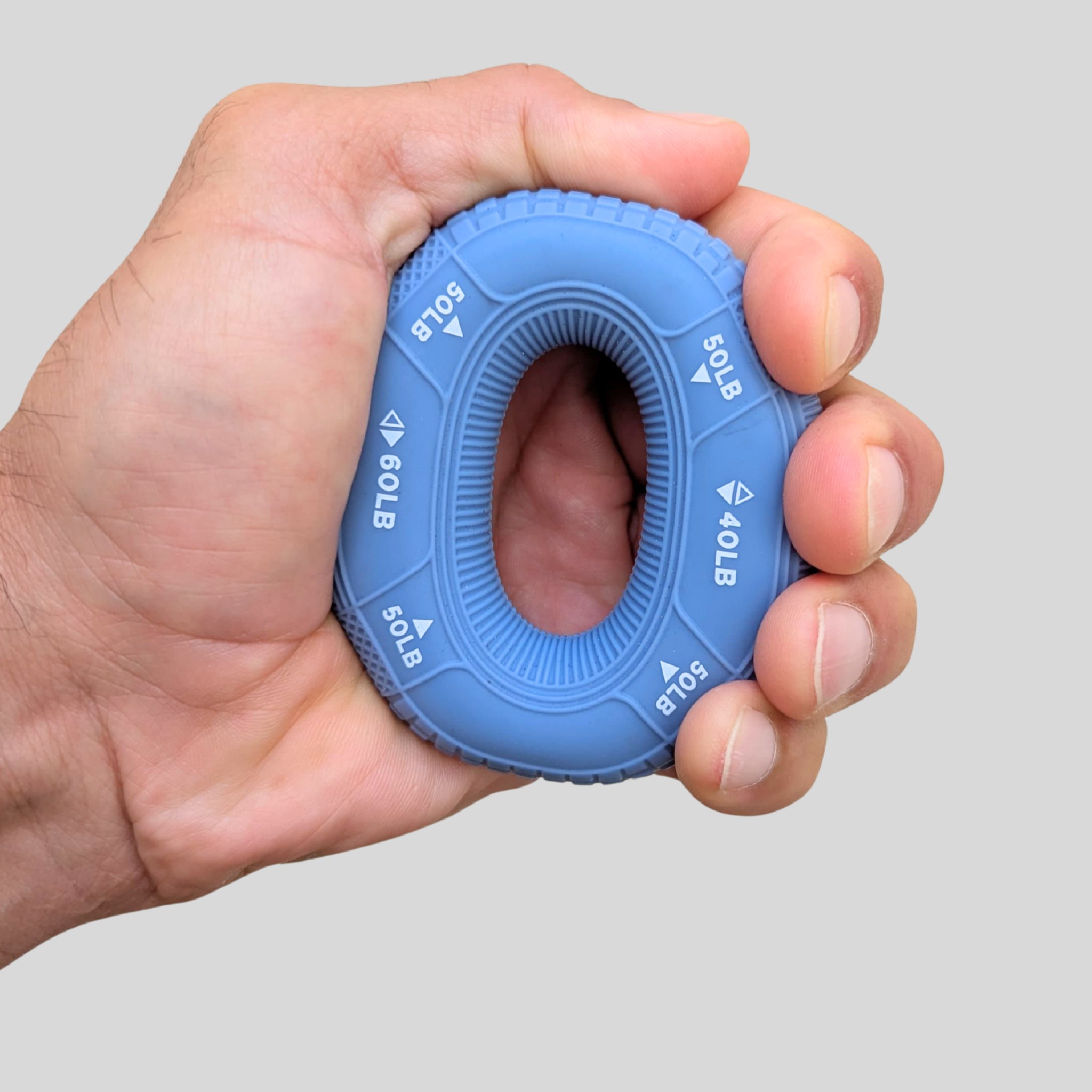 Mano che stringe l'anello blu del set POWER per allenare la forza di presa