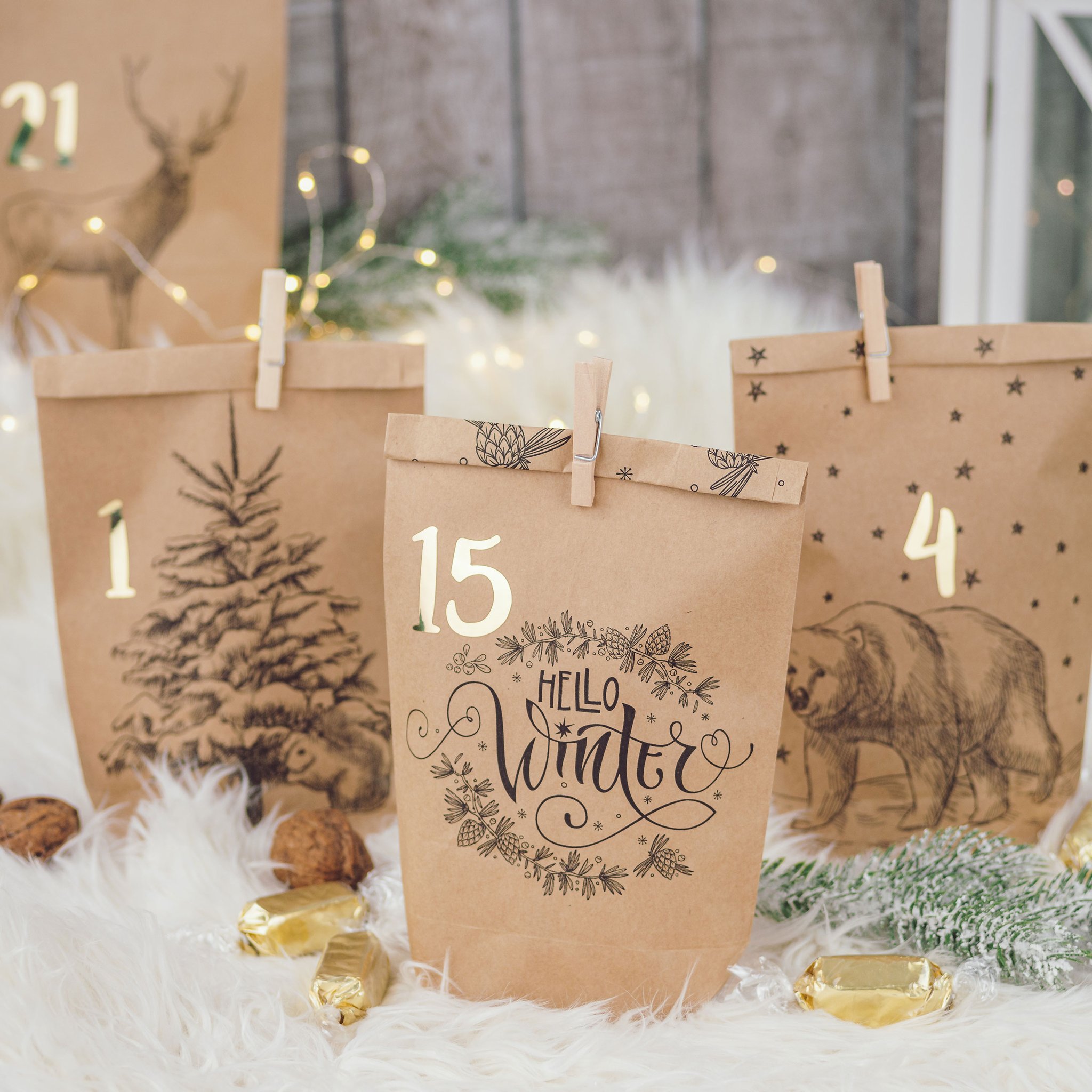DIY Adventskalender Cozy Winter: Kraftpapiertüten mit Tannen- und Hirschmotiven auf weissem Fell vor einer Laterne