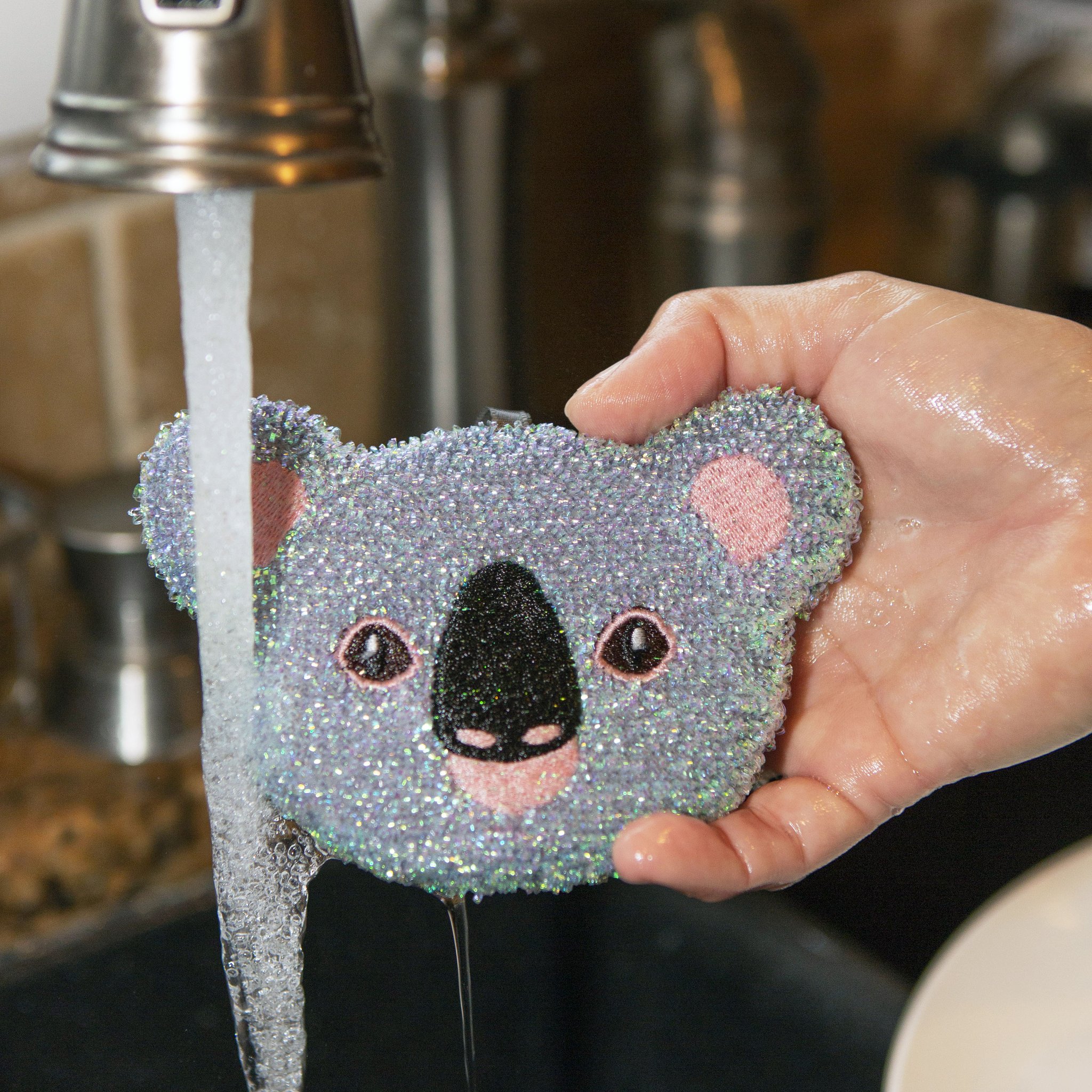 Spugna koala in mano sotto il rubinetto aperto