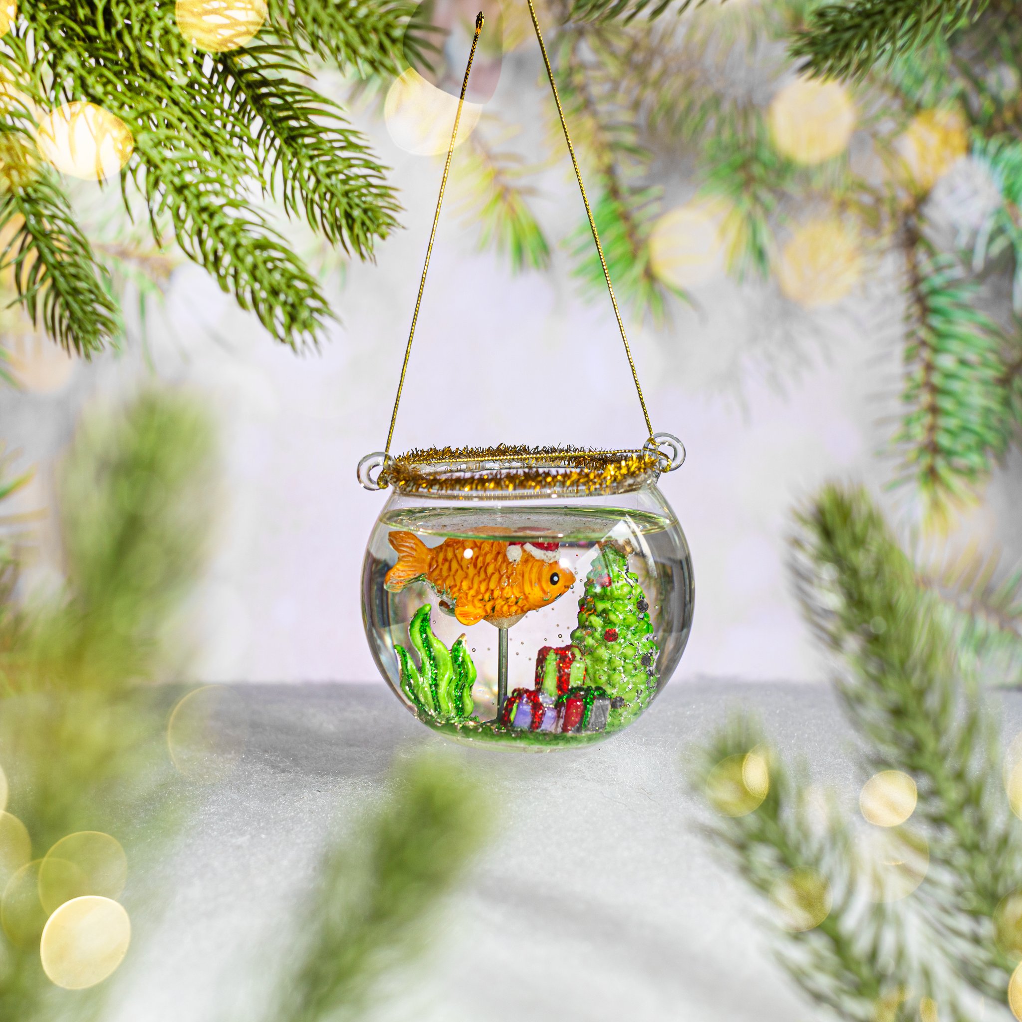 Fischglas Weihnachtskugel hängend am Tannenzweig mit goldenem Bokeh