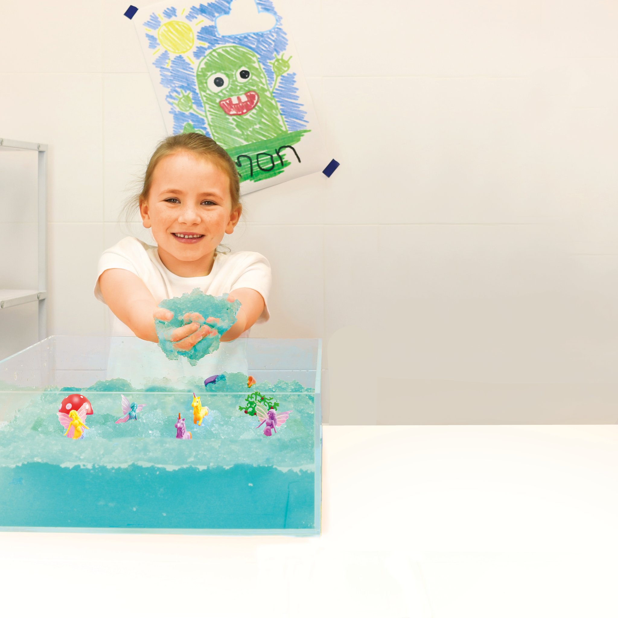 Girl playing with toy figures in a tub of aqua glitter slime
