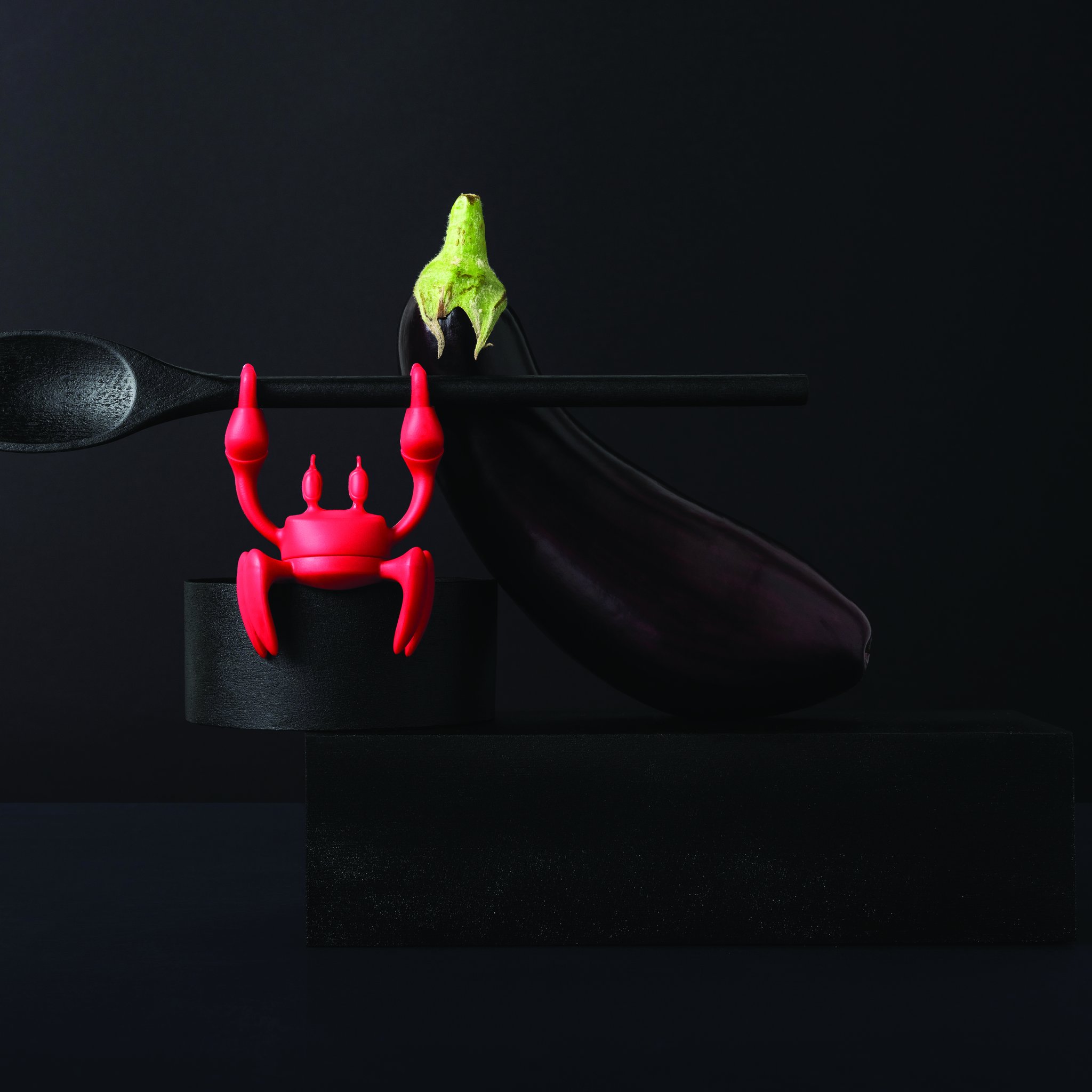 Red crab with a cooking spoon next to aubergines