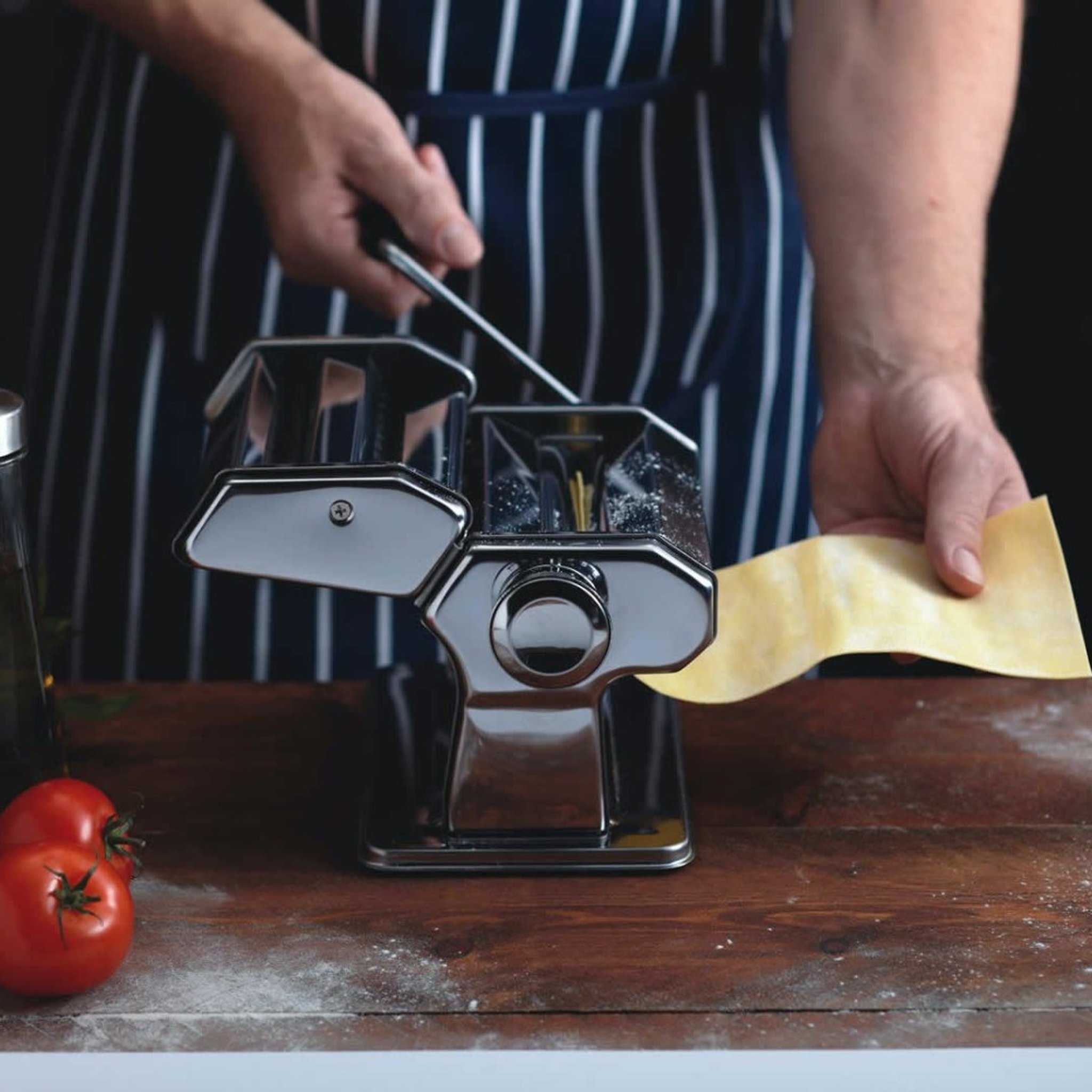 Macchina per pasta KitchenCraft Deluxe mentre stende la pasta con pomodori e olio d'oliva