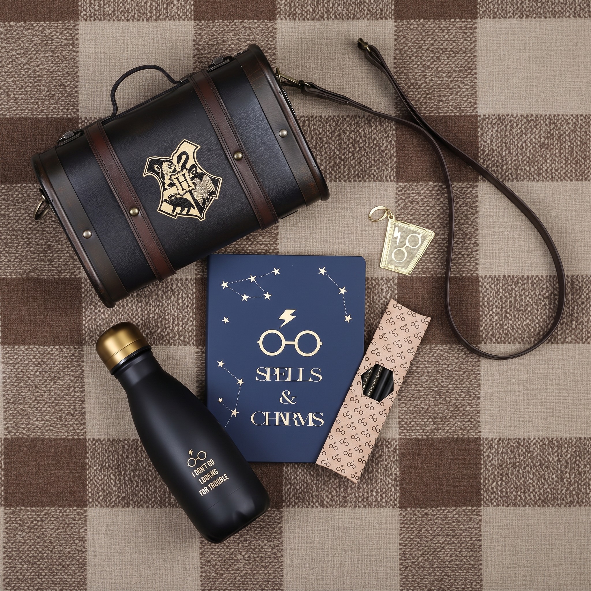 Inhalt des Harry Potter Geschenksets neben dem Hogwarts-Koffer auf kariertem Stoff