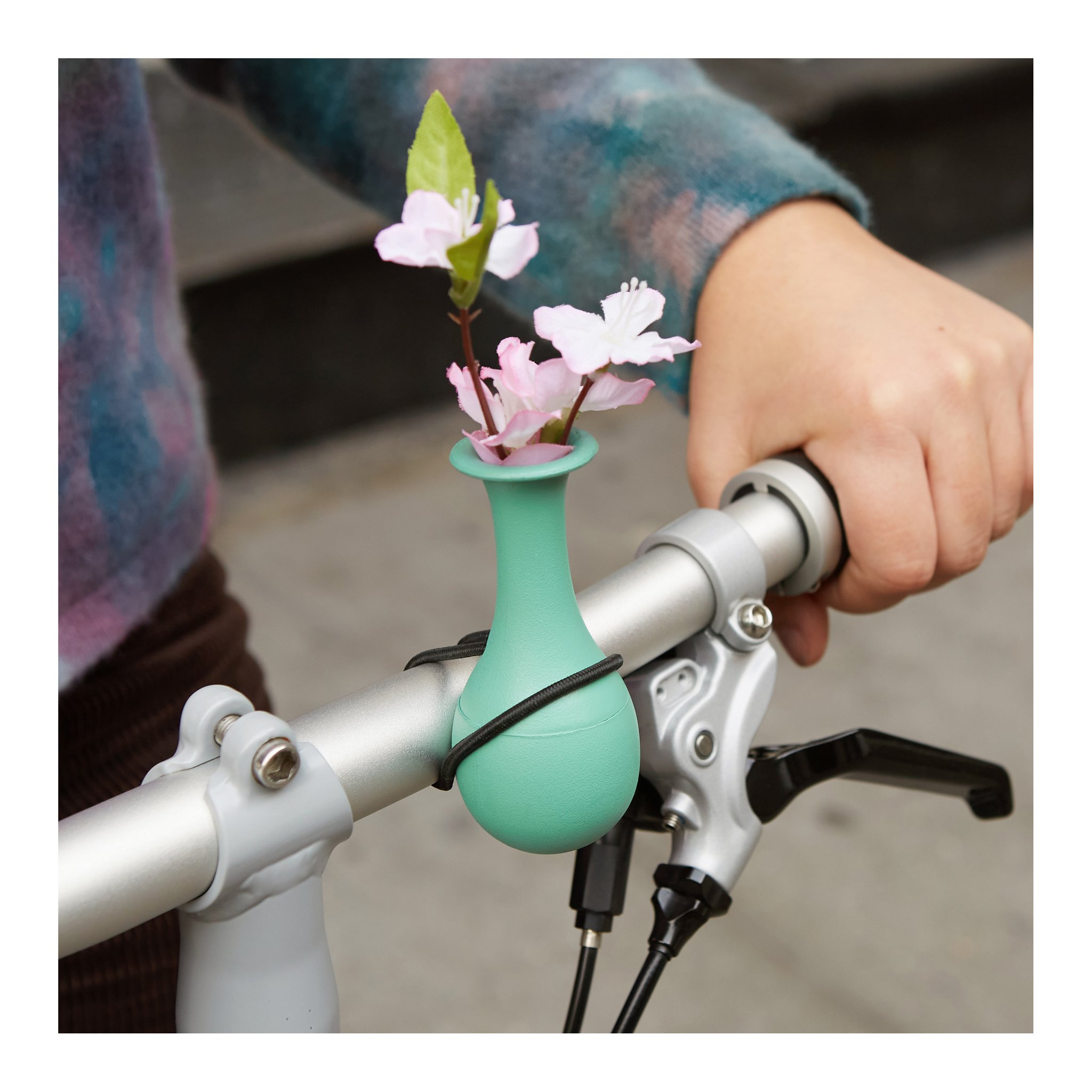 Vaso da bici con rametto di ciliegio sul manubrio, mano sull'impugnatura