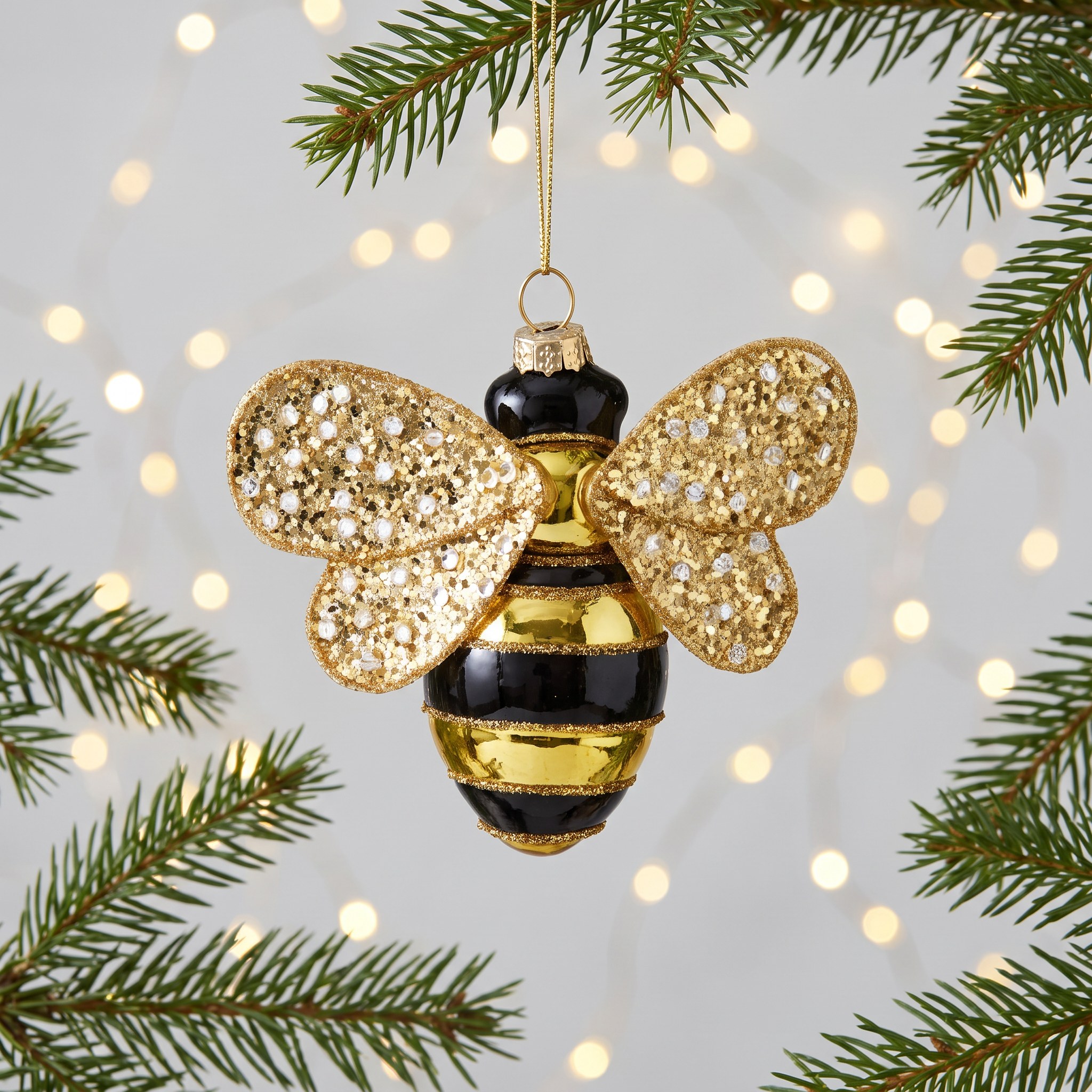 Bee Christmas Decoration by Sass & Belle on a fir branch with warm fairy lights