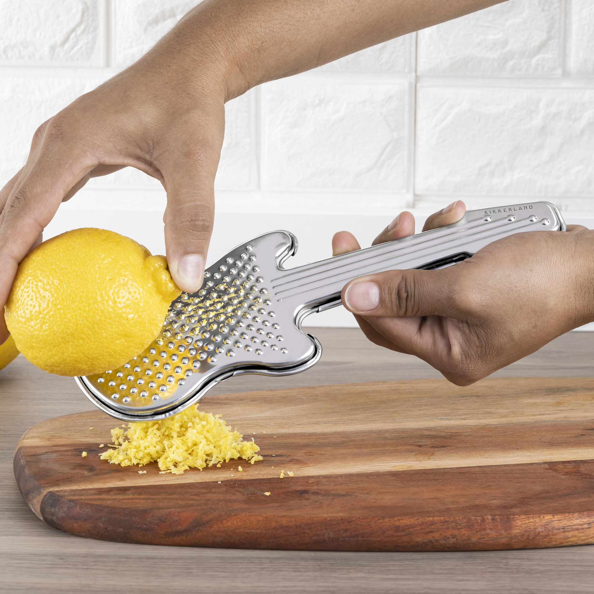 Mains râpant du zeste de citron avec la râpe guitare sur la planche