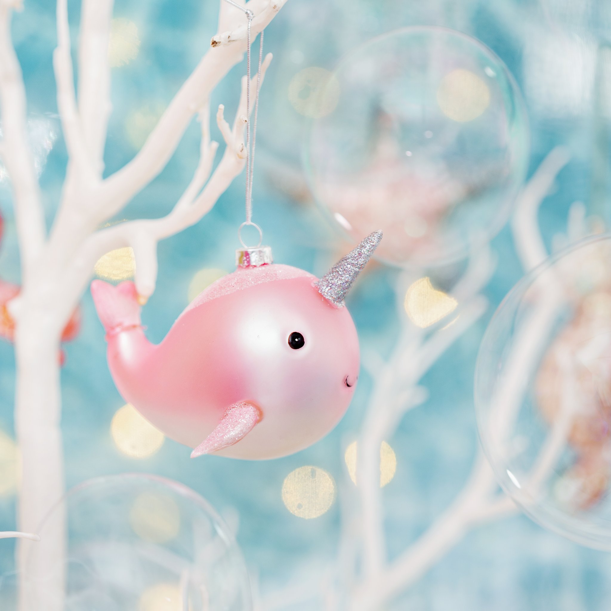 Boule de Noël narval suspendue parmi des branches de corail blanc avec bokeh