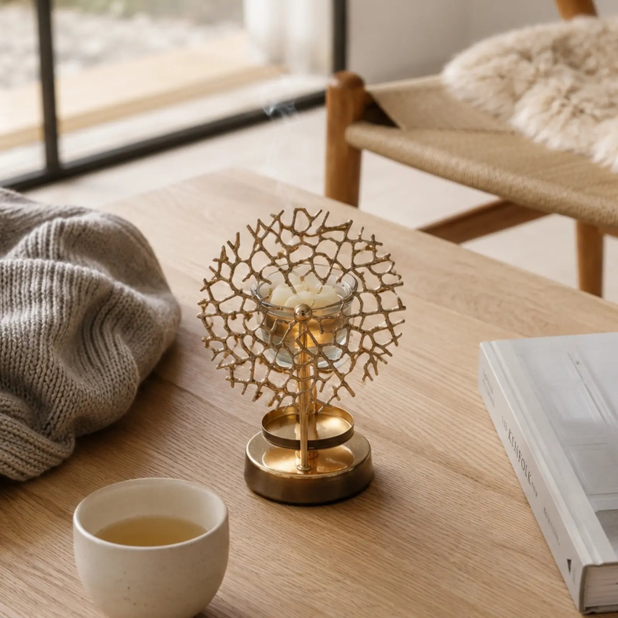 Coral pattern oil burner on a wooden table beside a tea bowl and a book