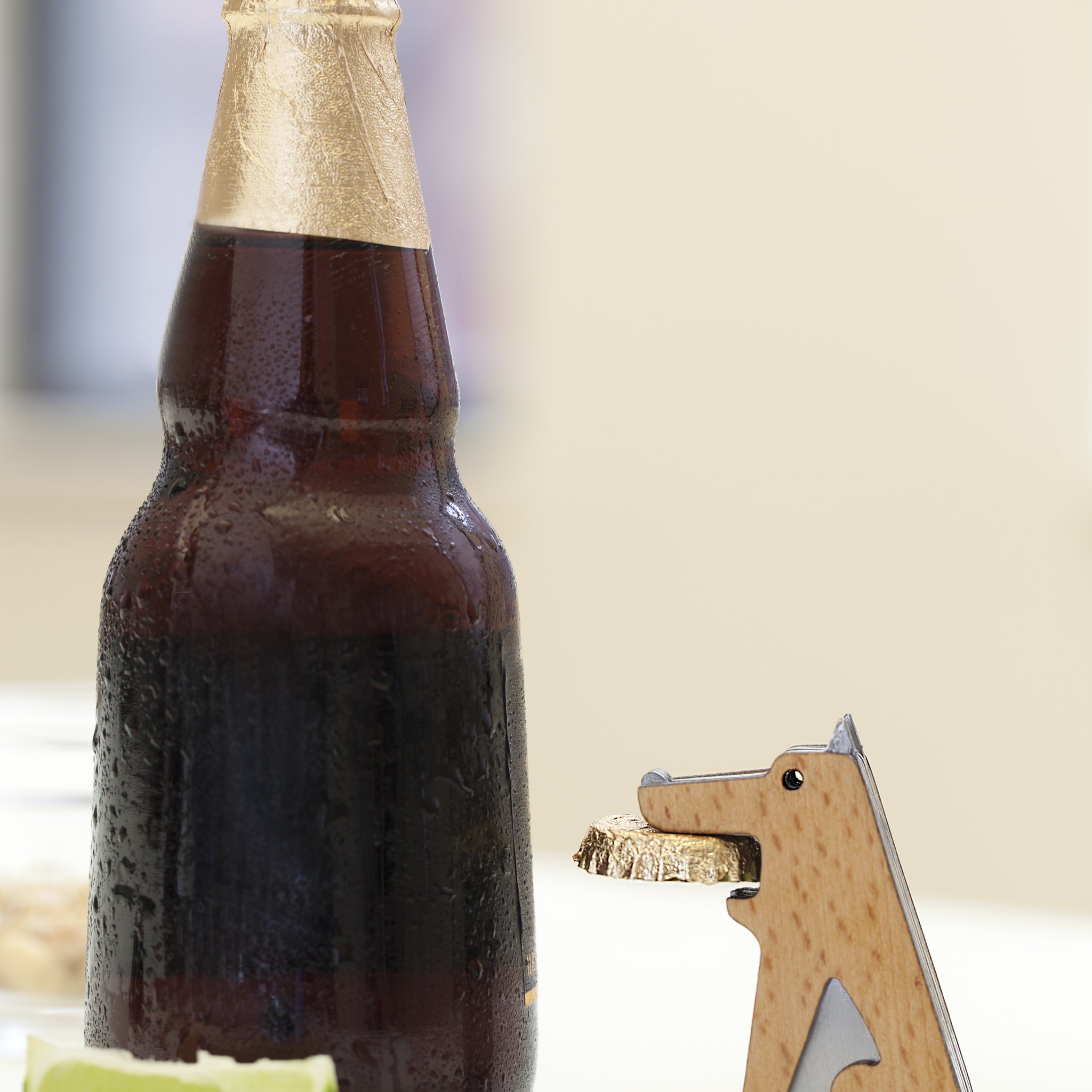 Fang!-Flaschenöffner mit Kronkorken im Maul neben Flasche und Limette