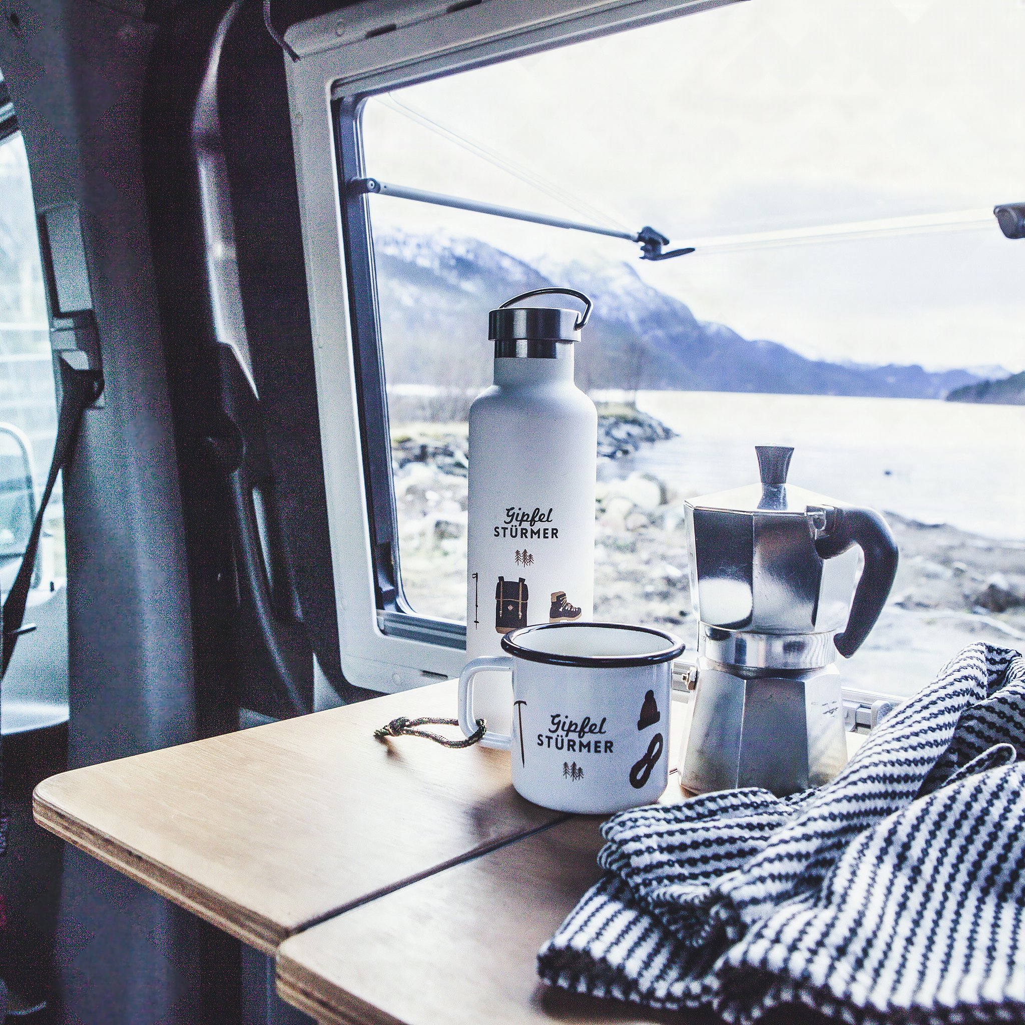 Gipfelstuermer Trinkflasche am Campervan-Fenster neben einer Espressokanne