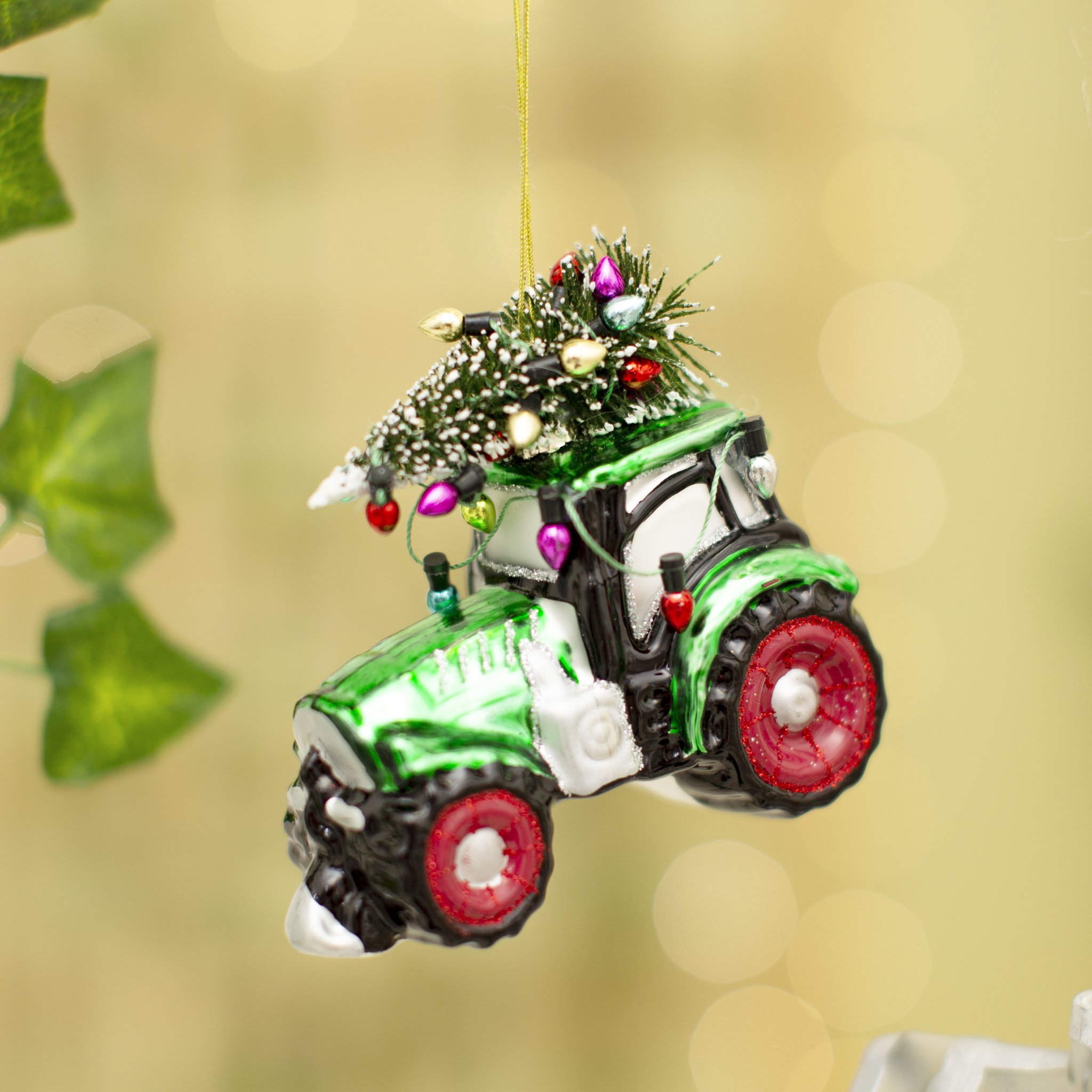 Décoration de sapin tracteur Sass & Belle, tracteur vert en verre avec sapin suspendu sur bokeh