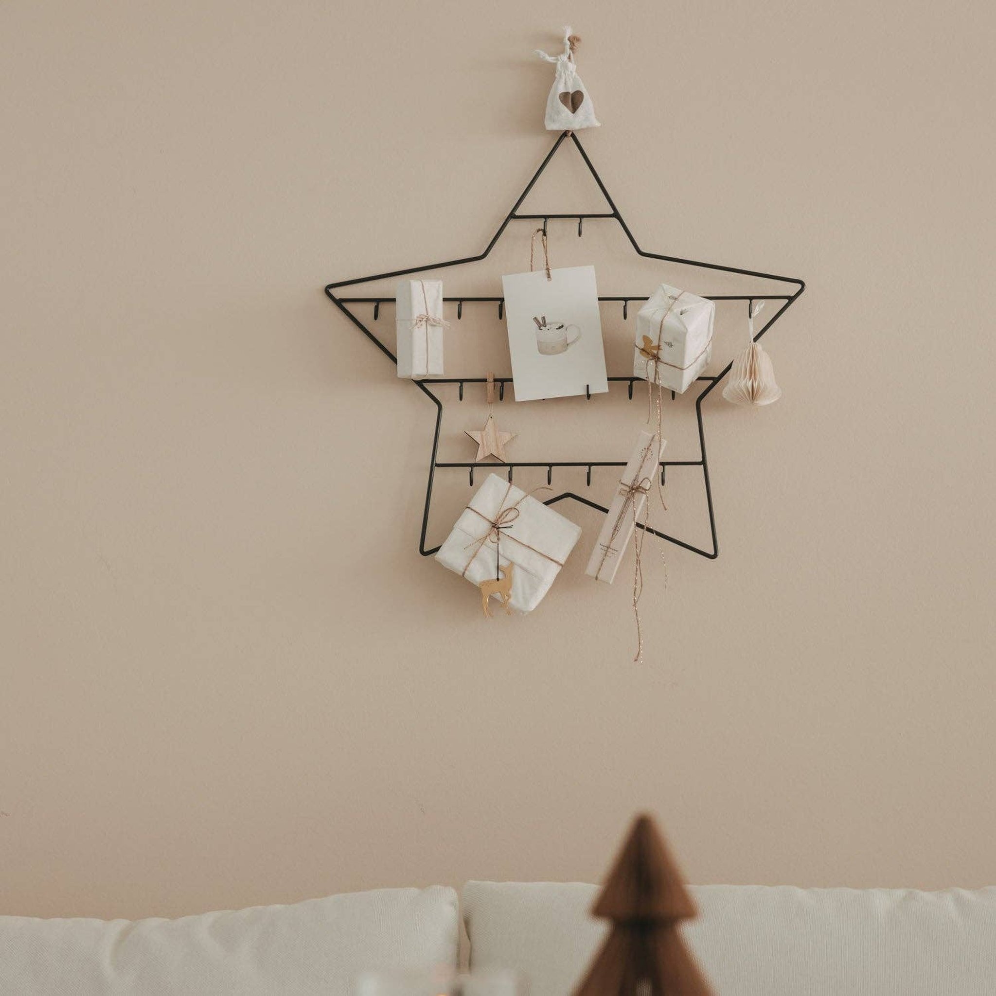 Star advent calendar above a sofa in a bright living room with a small wooden tree in front