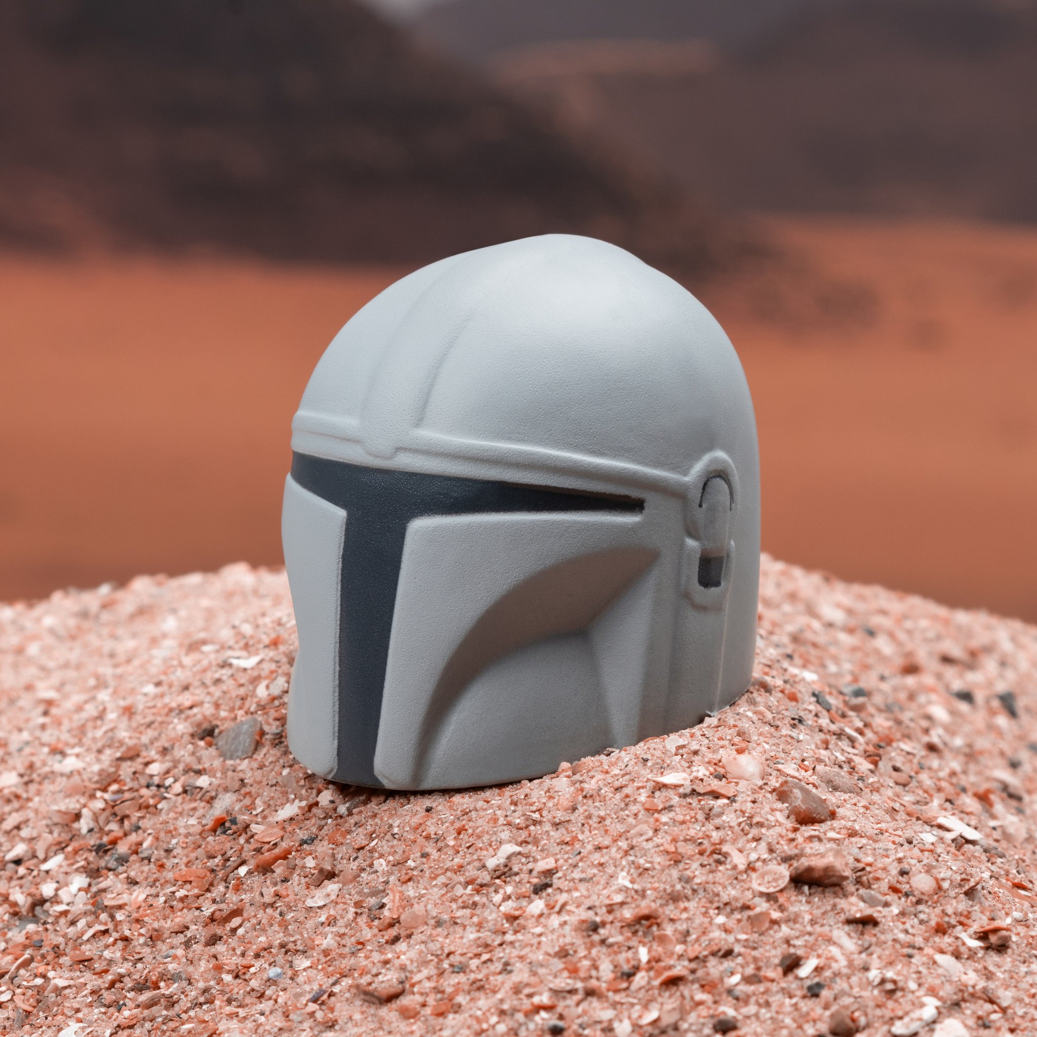 Palla antistress Mandalorian a forma di casco su sabbia rossa