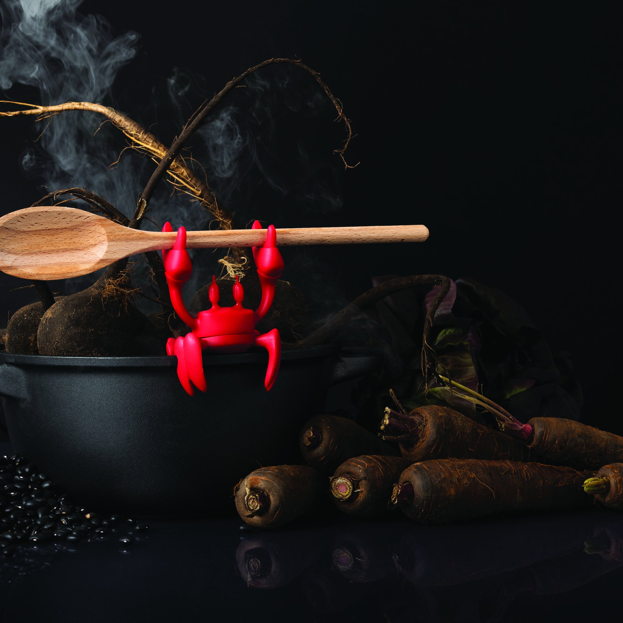Crabe rouge tenant une cuillère en bois au-dessus d'une casserole