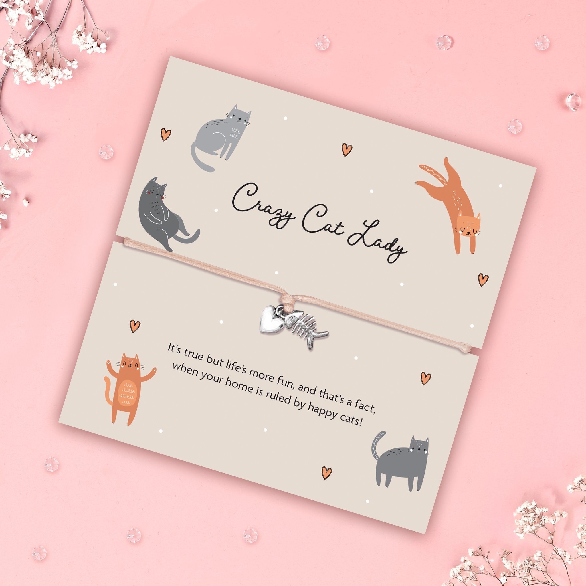 Katzenkarte mit Crazy-Cat-Lady-Armband schräg auf Rosa, umgeben von Schleierkraut und Glassteinen