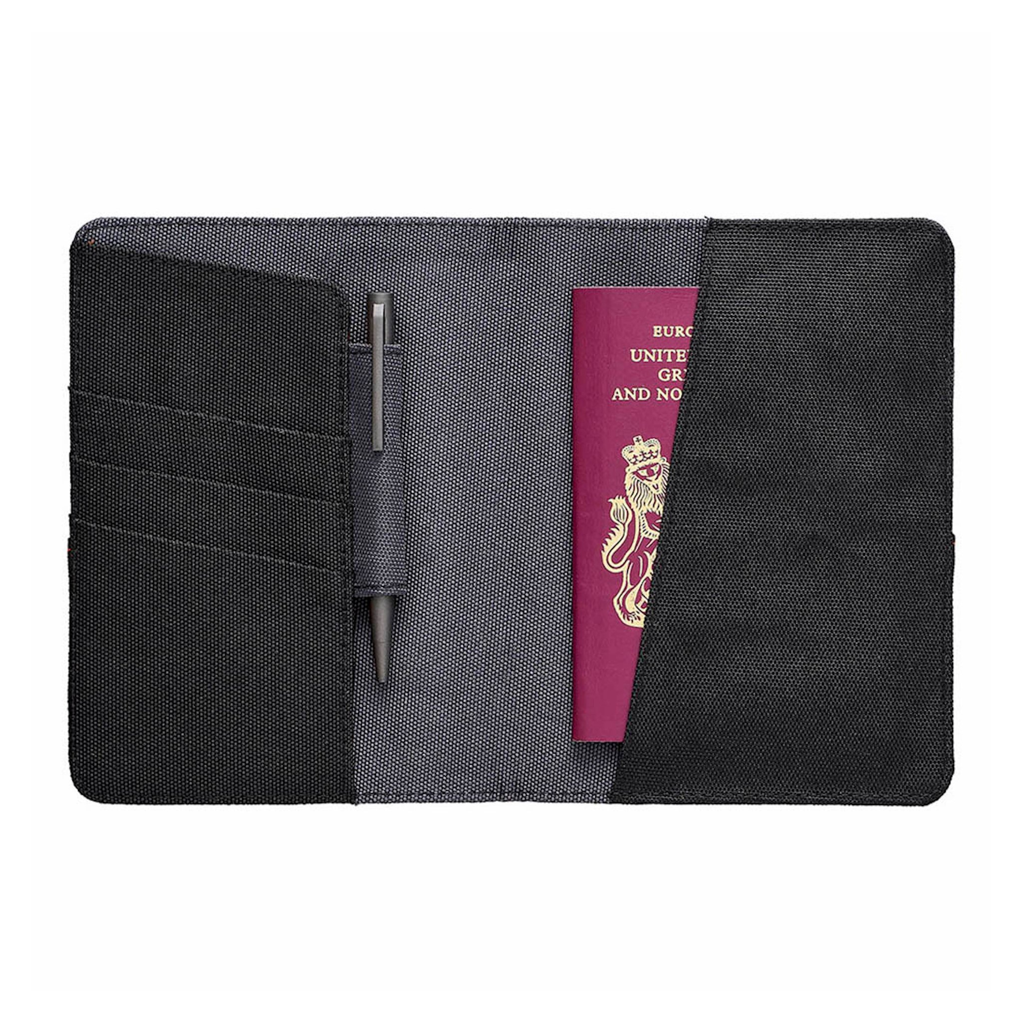 Aufgeklapptes Reise-Portemonnaie mit Kartenfächern, Stiftschlaufe mit Kugelschreiber und einem roten Reisepass in der Tasche