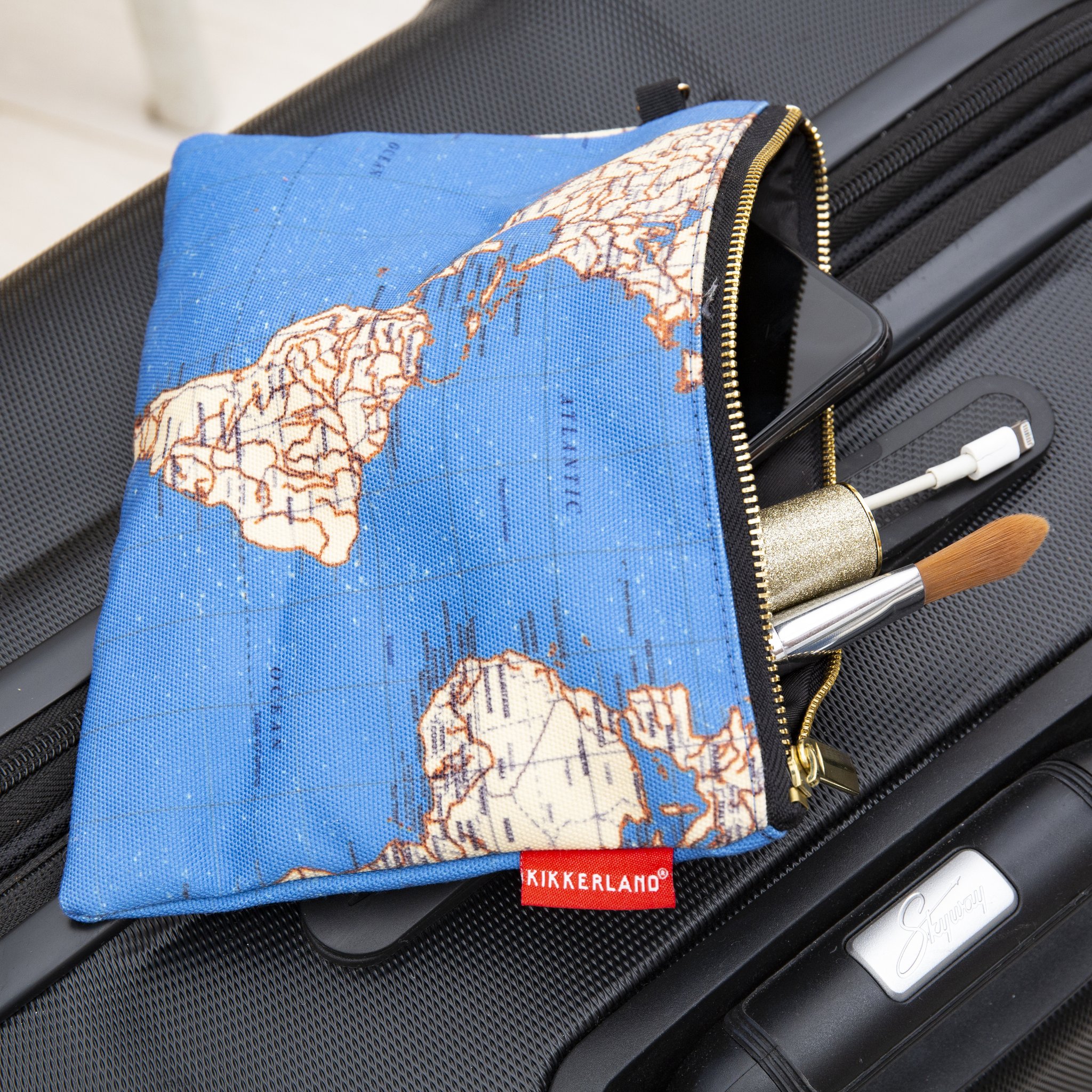 Globetrotter-Tasche mit Weltkarte offen auf einem Koffer, Pinsel schauen heraus