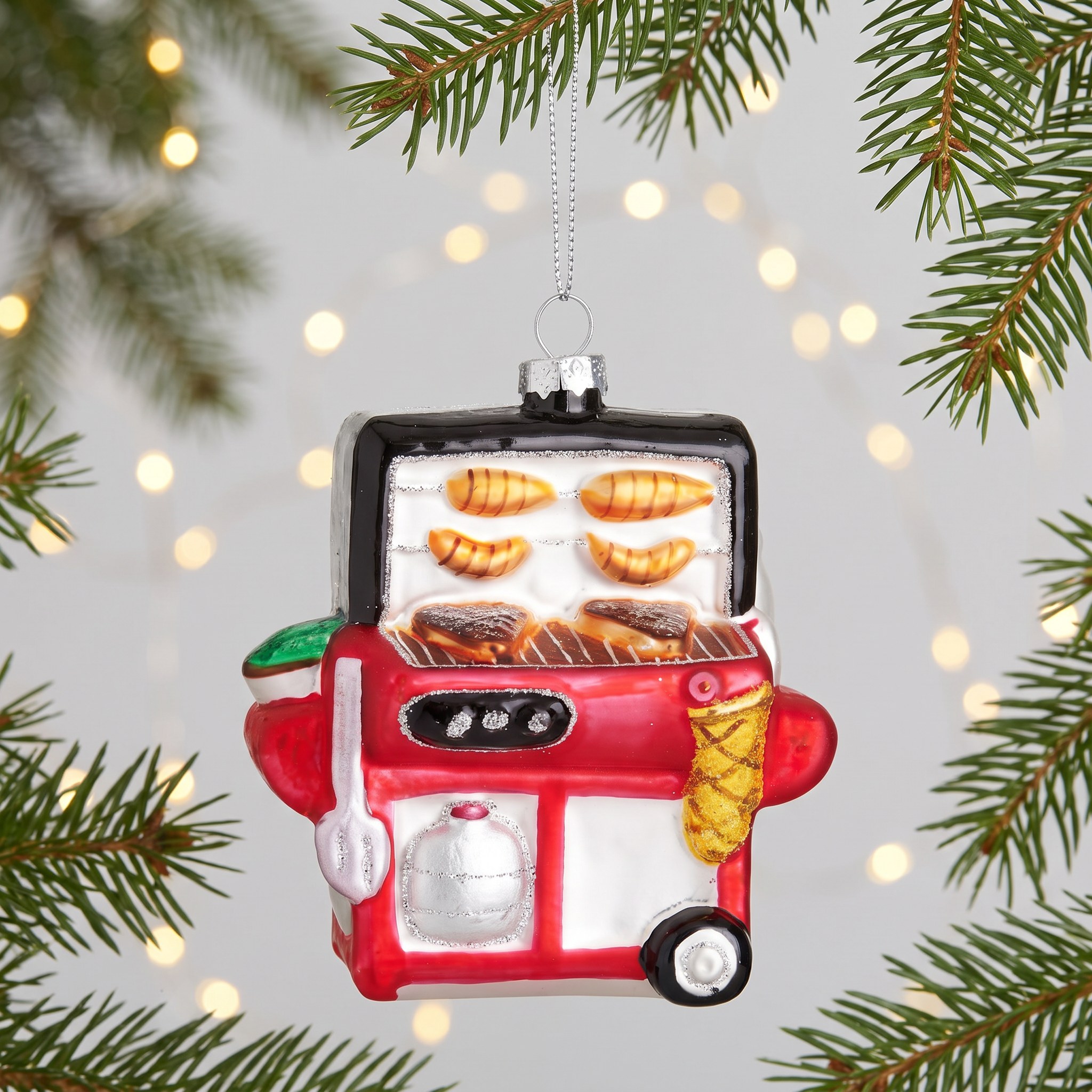 BBQ Shaped Bauble by Sass & Belle on a fir branch with warm fairy lights