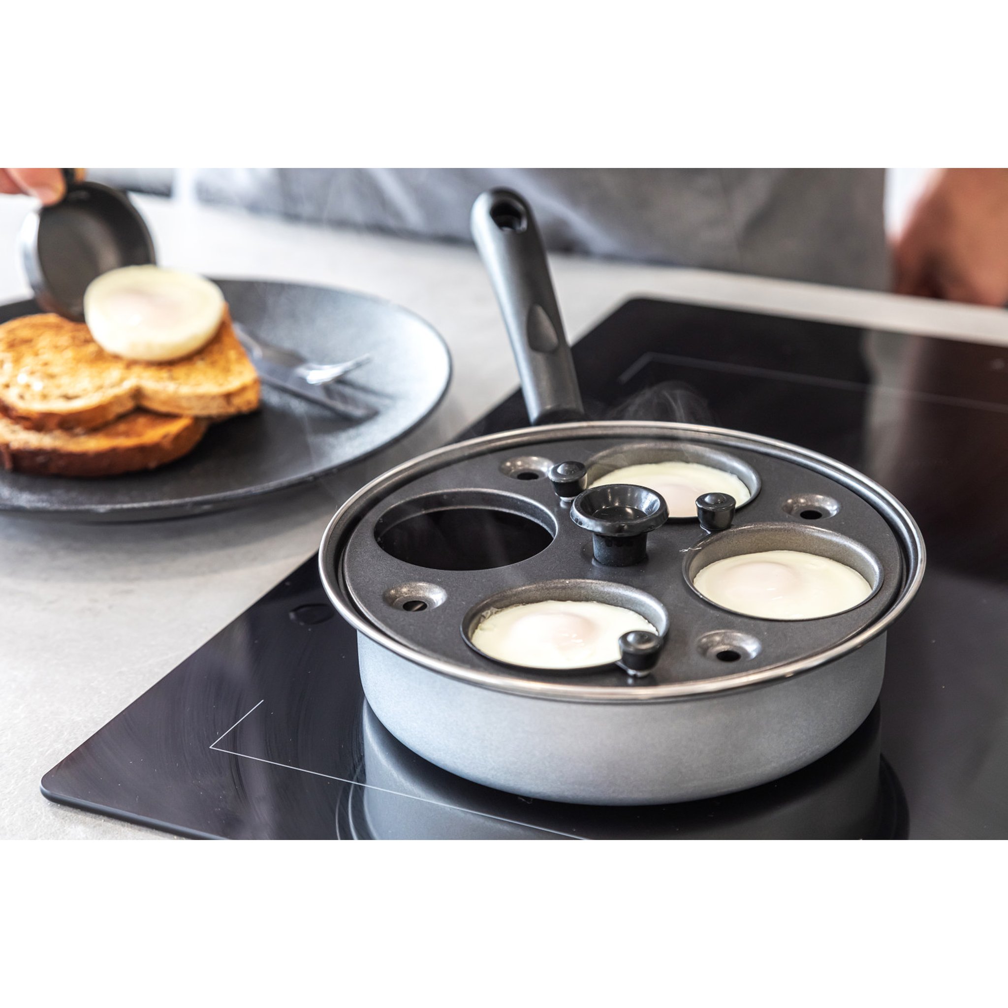 Egg poacher on induction hob with poached egg and toast