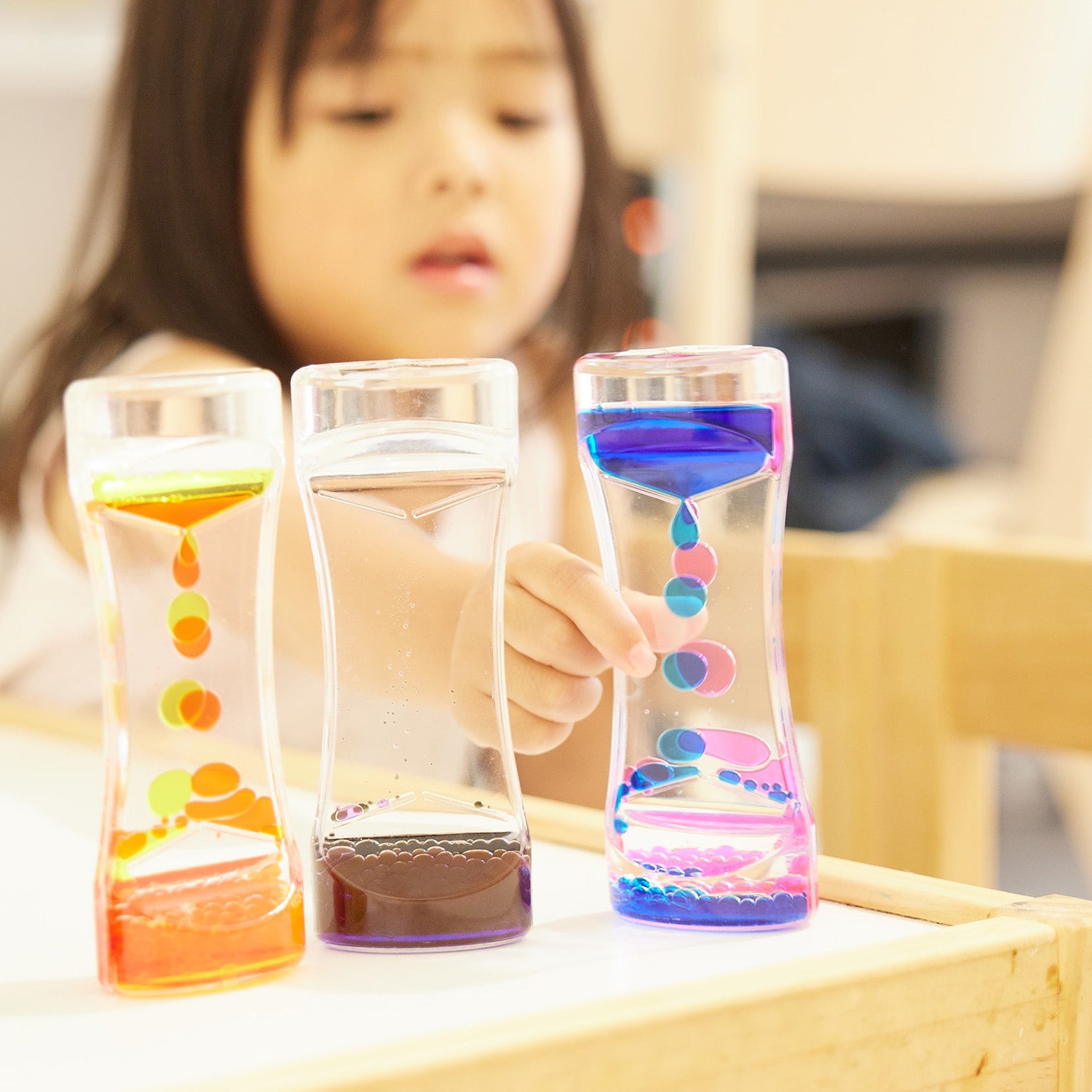 Enfant jouant avec les sabliers lampes à lave colorés