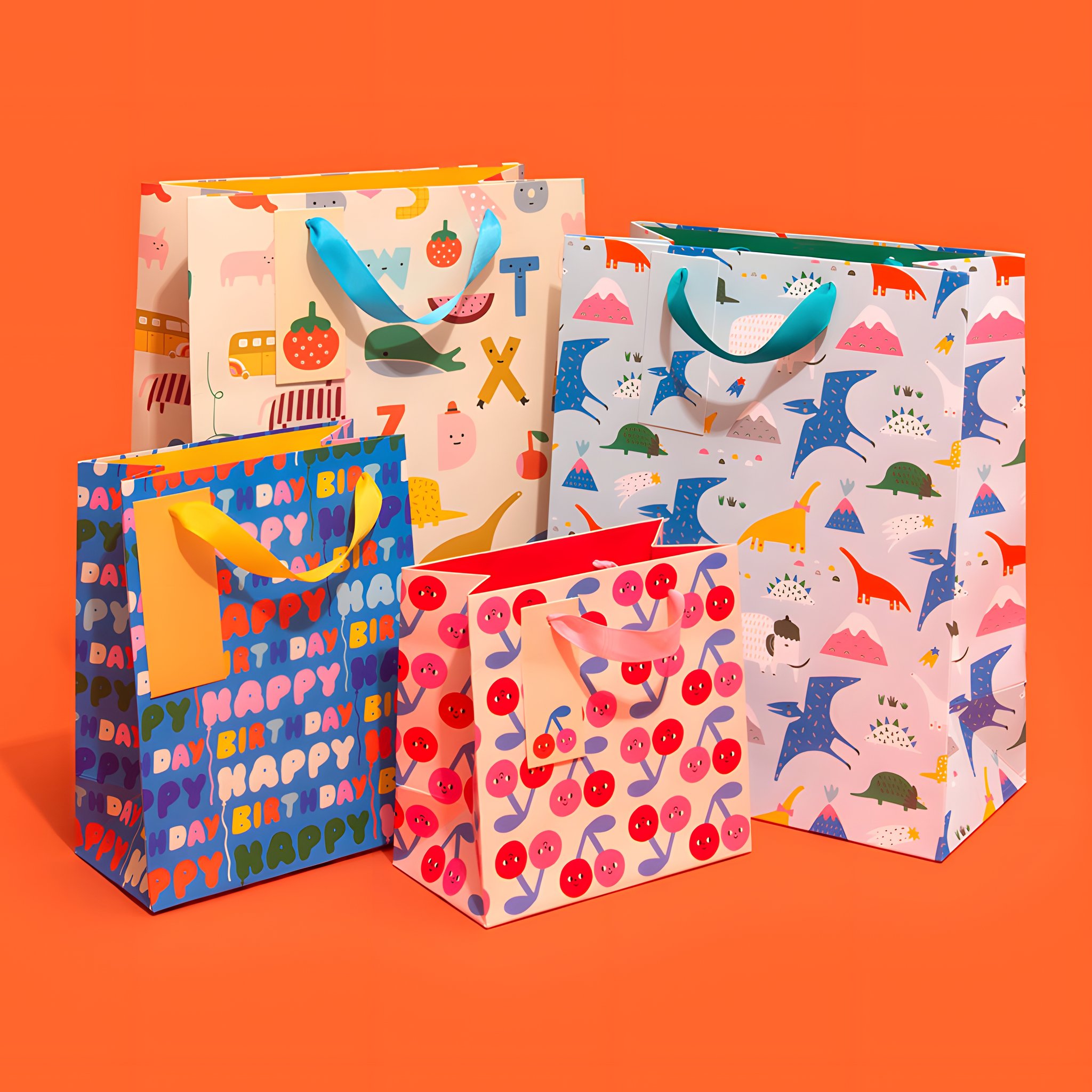 Busta regalo grande con alfabeto colorato insieme ad altre buste regalo Ohh Deer su sfondo colorato